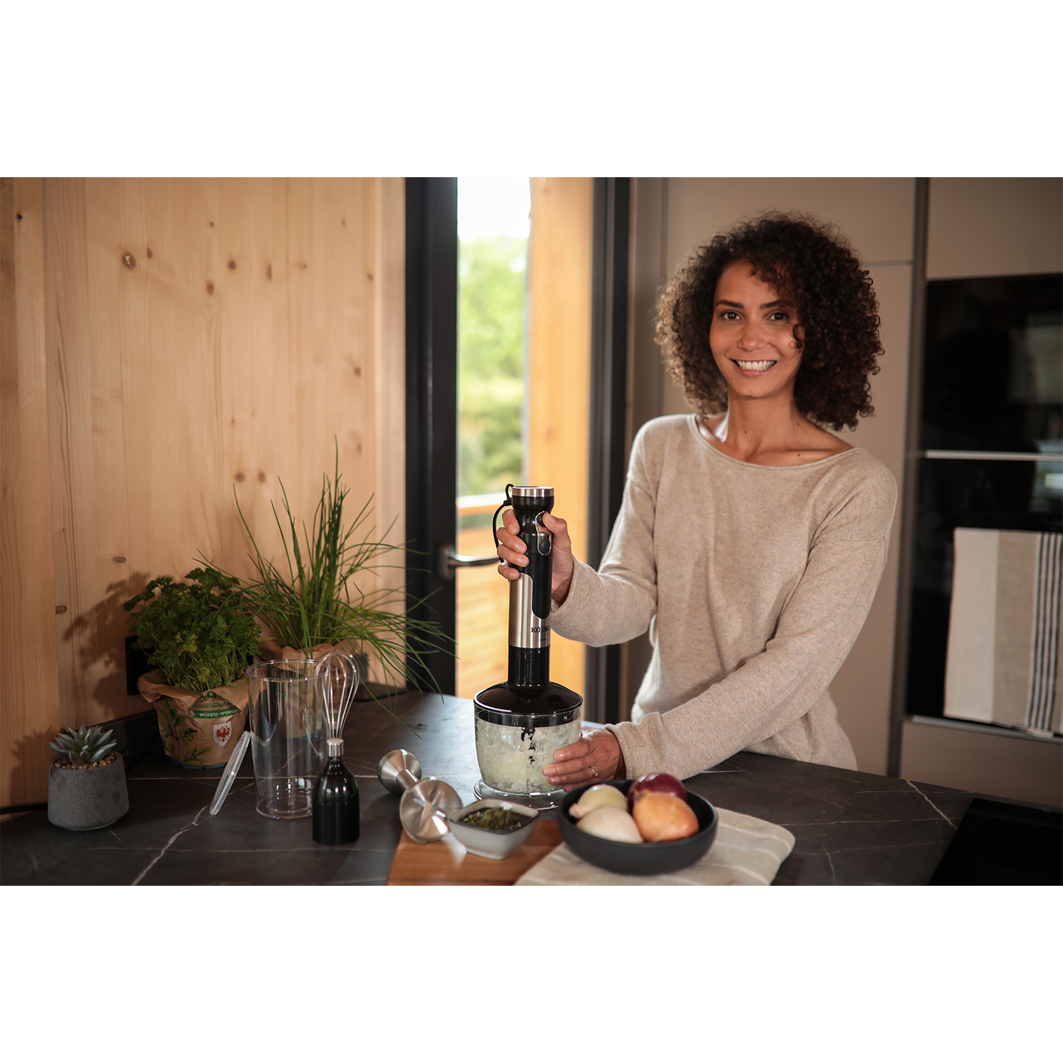 Donna che usa un frullatore a immersione con cipolle e altri ingredienti.