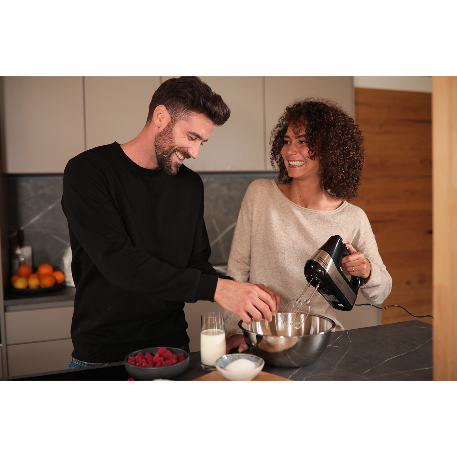 Una coppia sorridente che prepara qualcosa con un mixer.