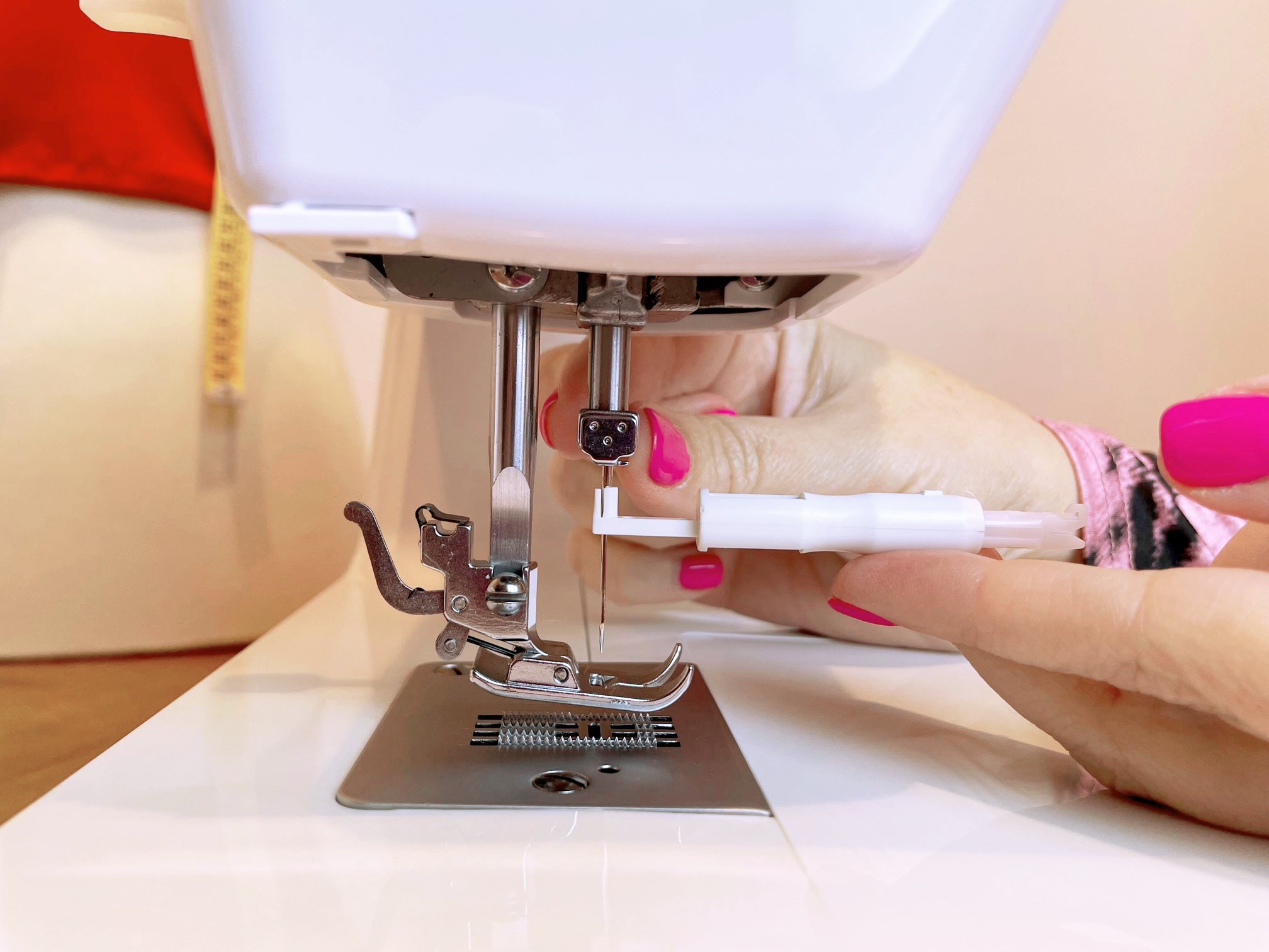Las manos de una persona insertando una aguja en una máquina de coser.