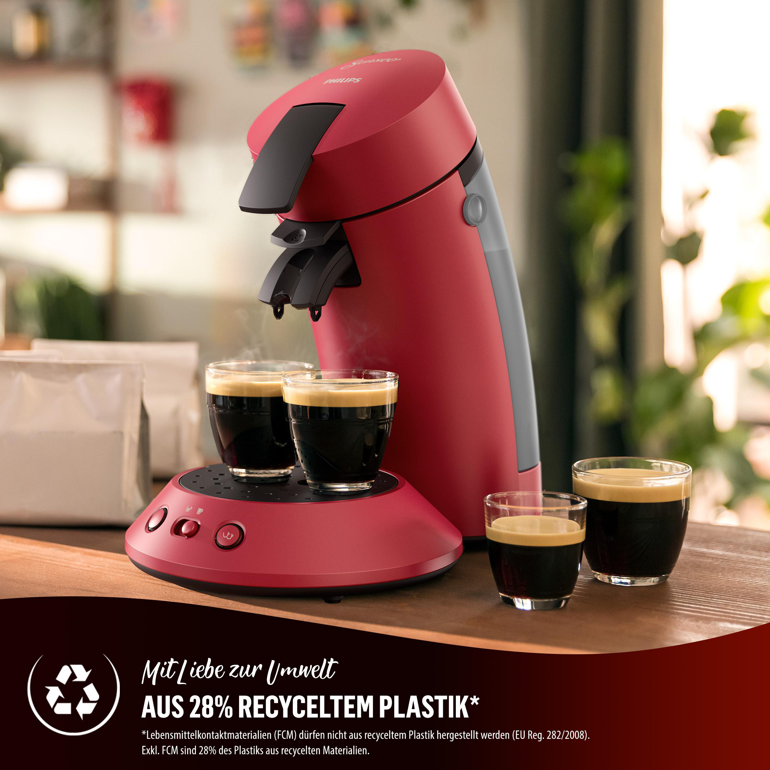 Rote Philips Senseo Kaffeemaschine. Zwei Tassen Kaffee auf der Warmhalteplatte. Text über recyceltes Plastik.