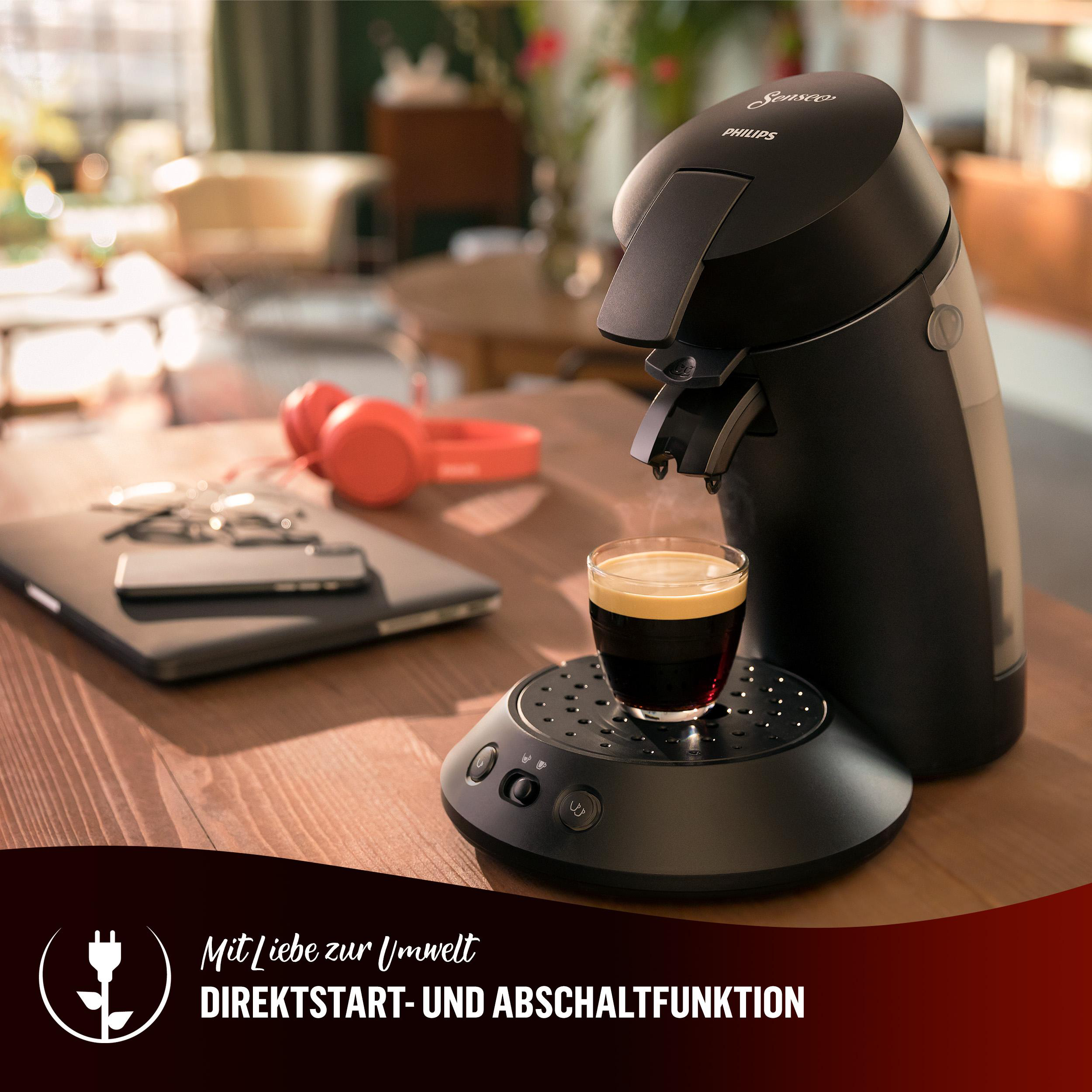 Schwarze Kaffeemaschine mit Kaffeeglas, Schlüsseln und roten Kopfhörern.