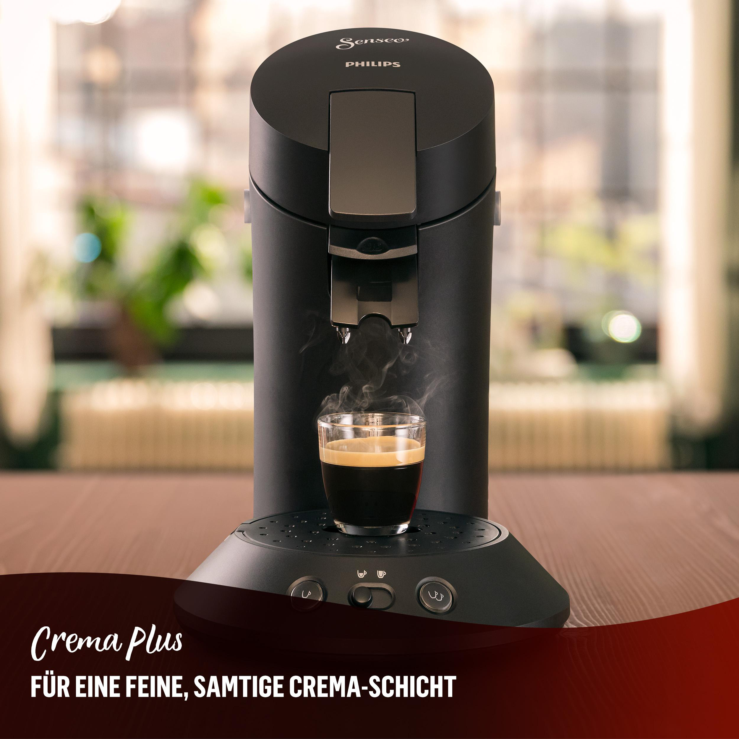 Eine schwarze Kaffeemaschine mit einem Glas Kaffee. Der Text „Crema Plus“ ist sichtbar.