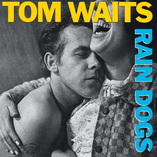 Albumcover mit Tom Waits und umarmender Frau, die lacht. Titel 'Rain Dogs' in Blau rechts.