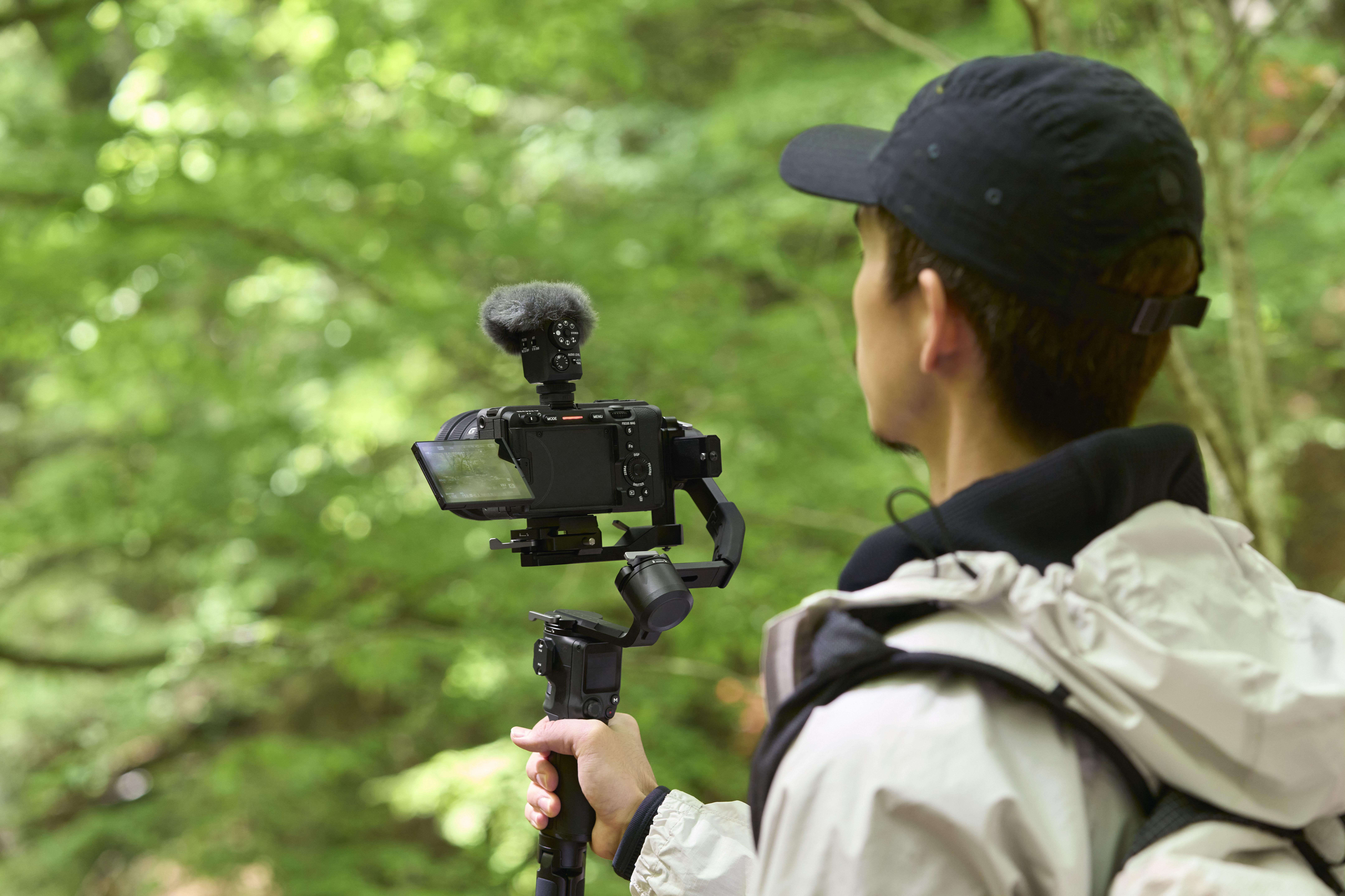 Eine Person filmt mit einer Kamera auf einem Gimbal in einem Wald.