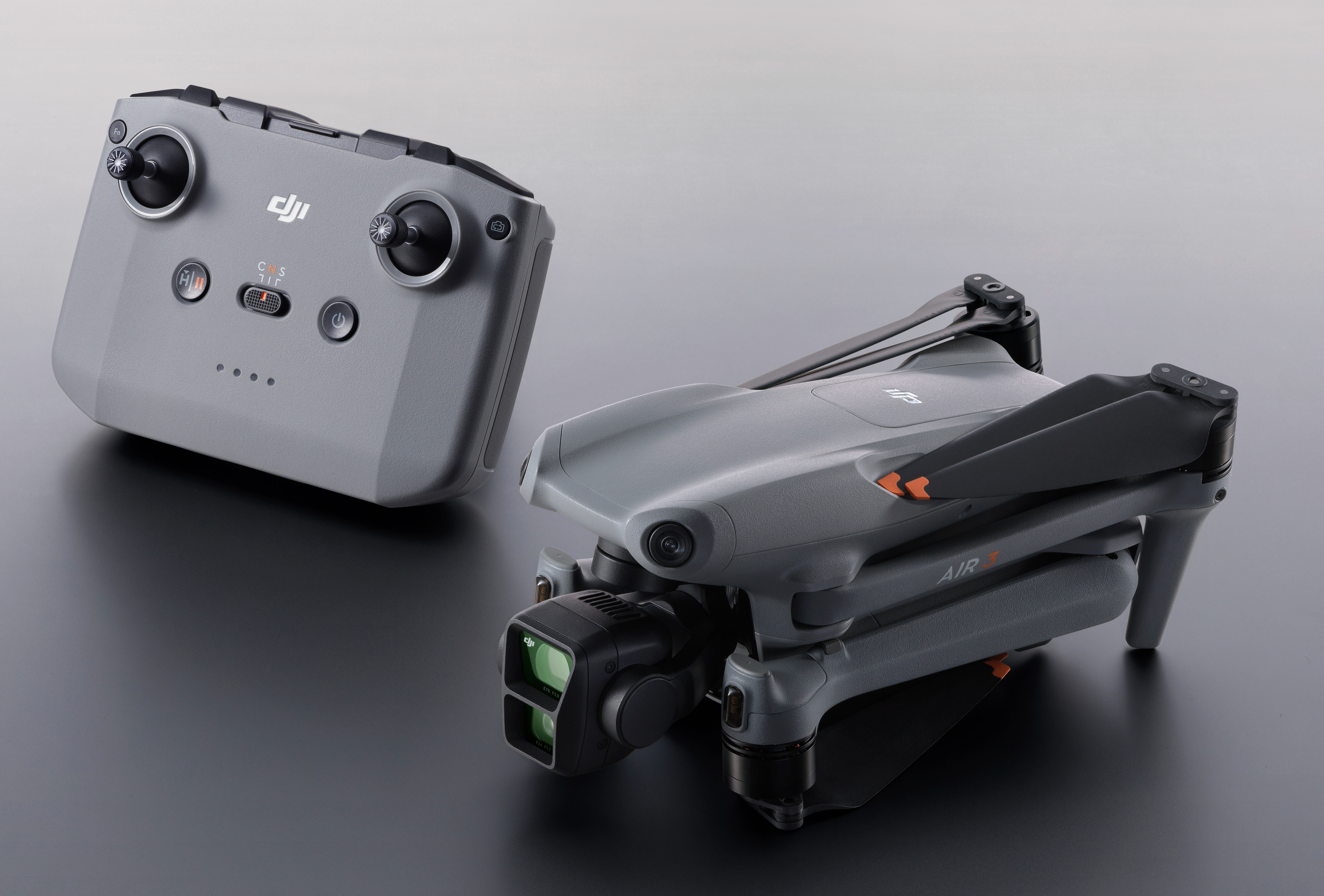 Drone grigio e il suo telecomando su una superficie scura. Il drone è ripiegato.