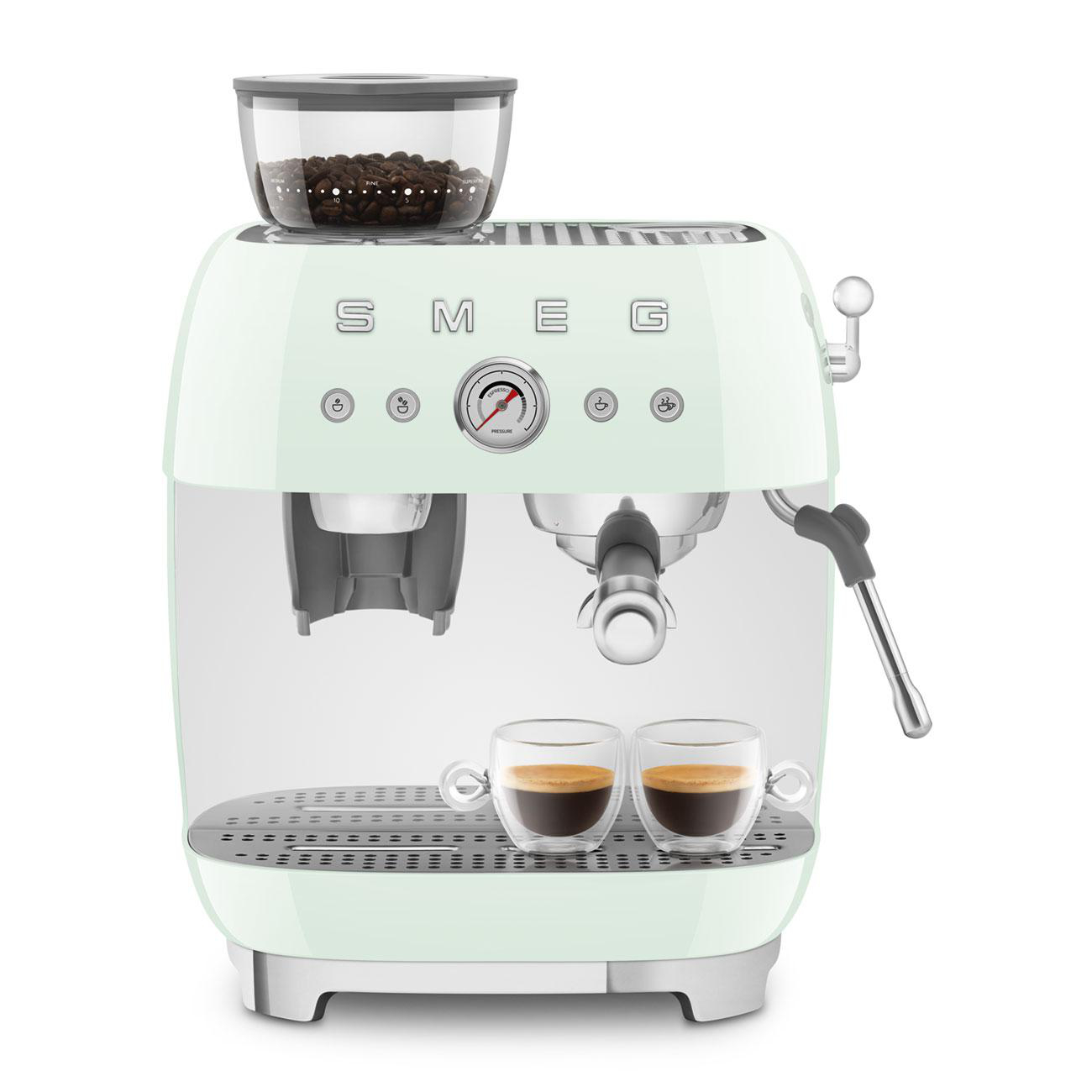 Minzgrüner SMEG-Espressomaschine. Kaffeebohnen im Mahlwerk, zwei Tassen Kaffee auf dem Tablett.