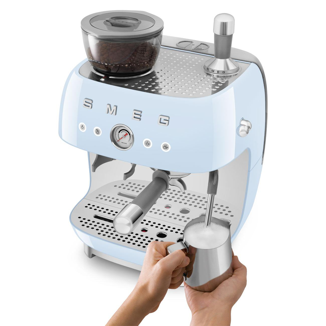 Hellblaue Smeg Espressomaschine mit integrierter Kaffeemühle und Hand beim Milchaufschäumen.