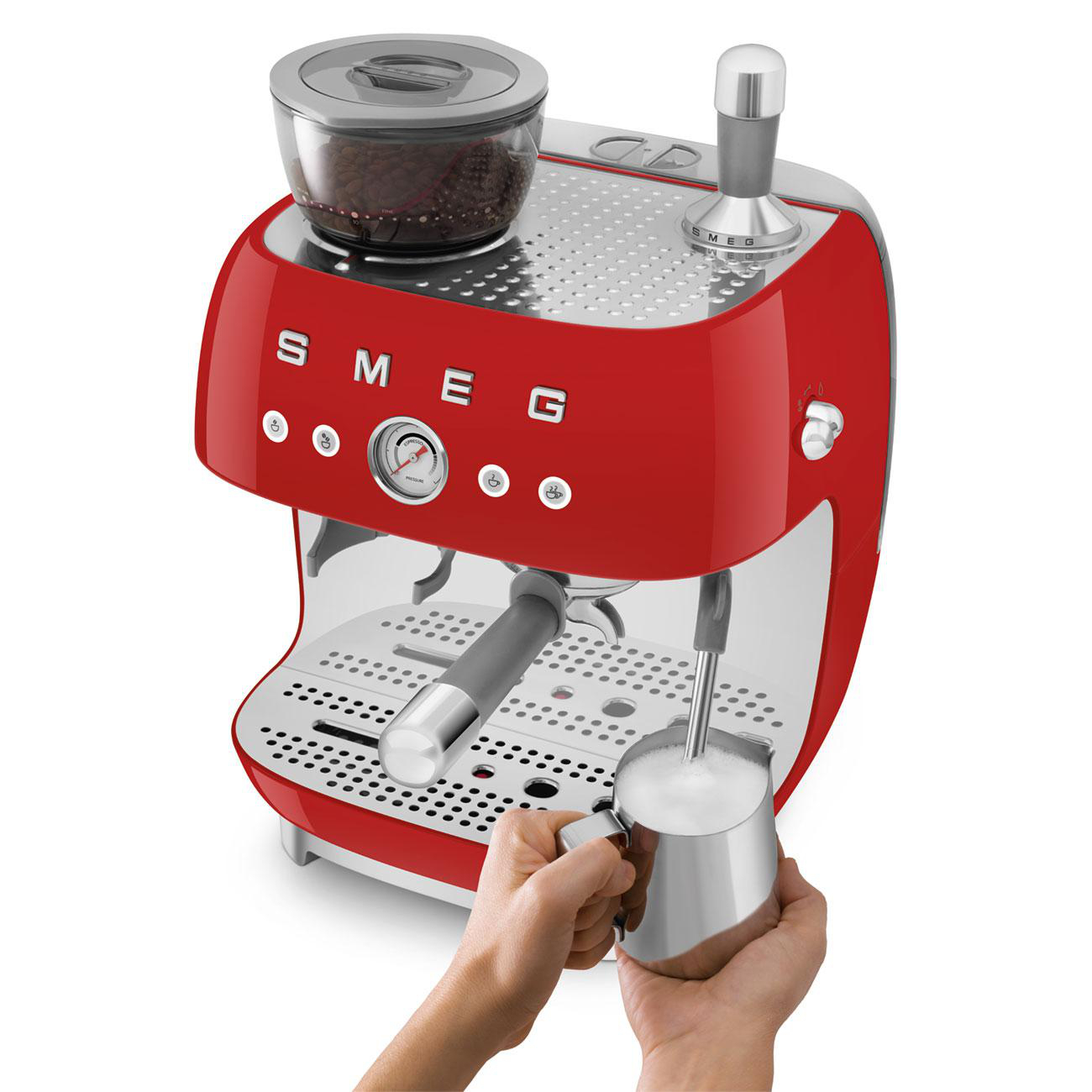 Rote Smeg Espressomaschine mit Kaffeemühle. Eine Hand hält einen Milchaufschäumer.