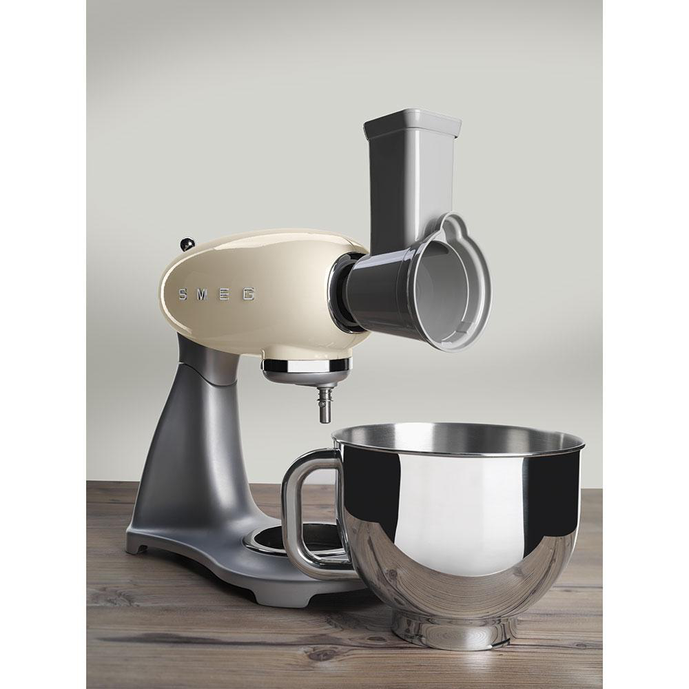 Ein beige-silberner SMEG-Küchenmixer mit Aufsatz auf einer Holzoberfläche.