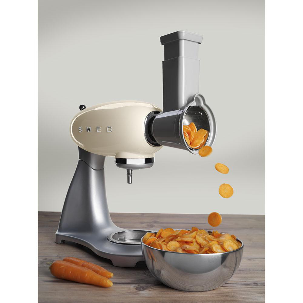 Cremefarbener SMEG-Küchenmaschine mit Karotten, die in eine Schüssel geschnitten werden. Holzoberfläche.