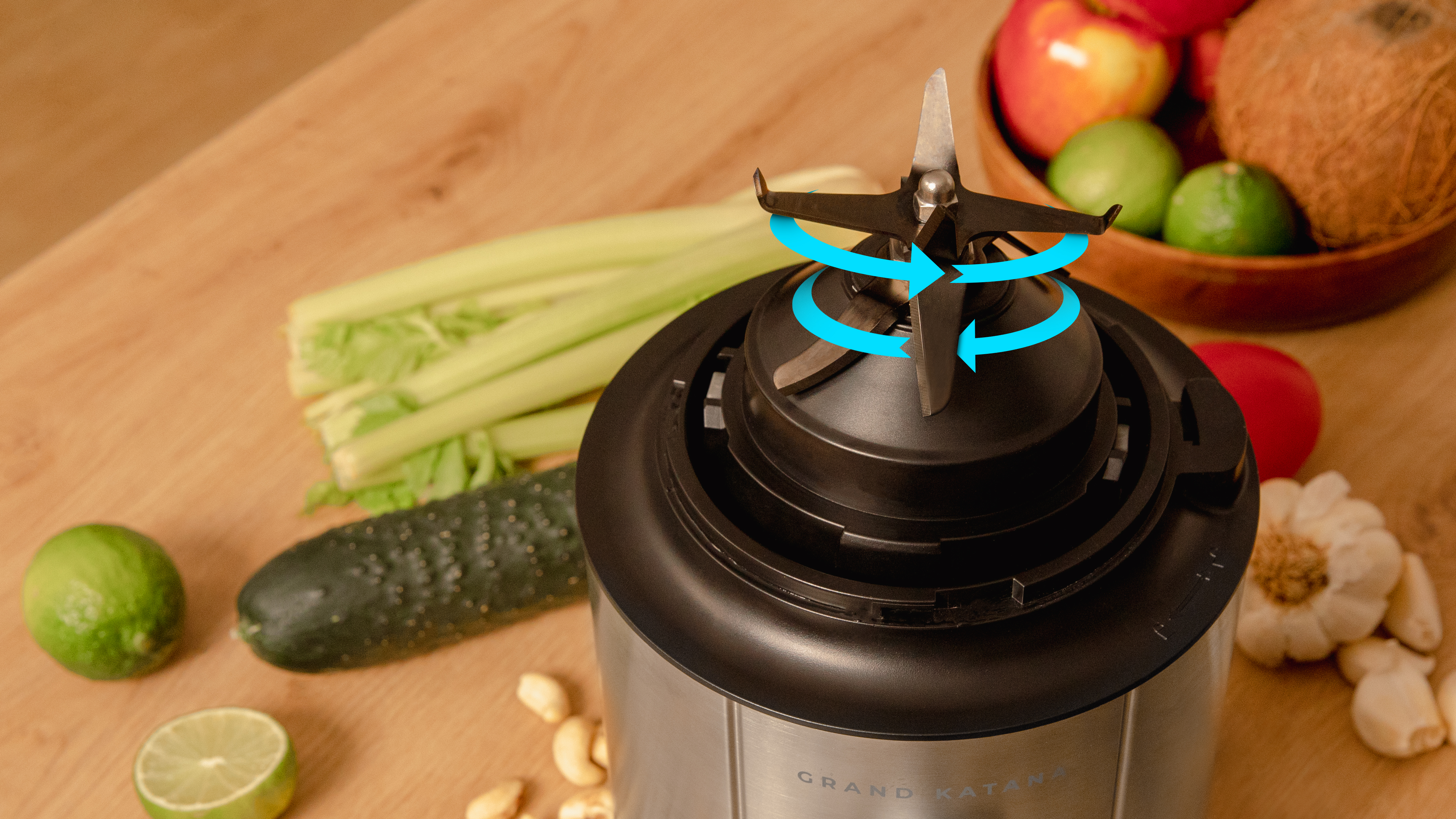 Una licuadora con cuchillas giratorias, rodeada de frutas y verduras sobre madera.