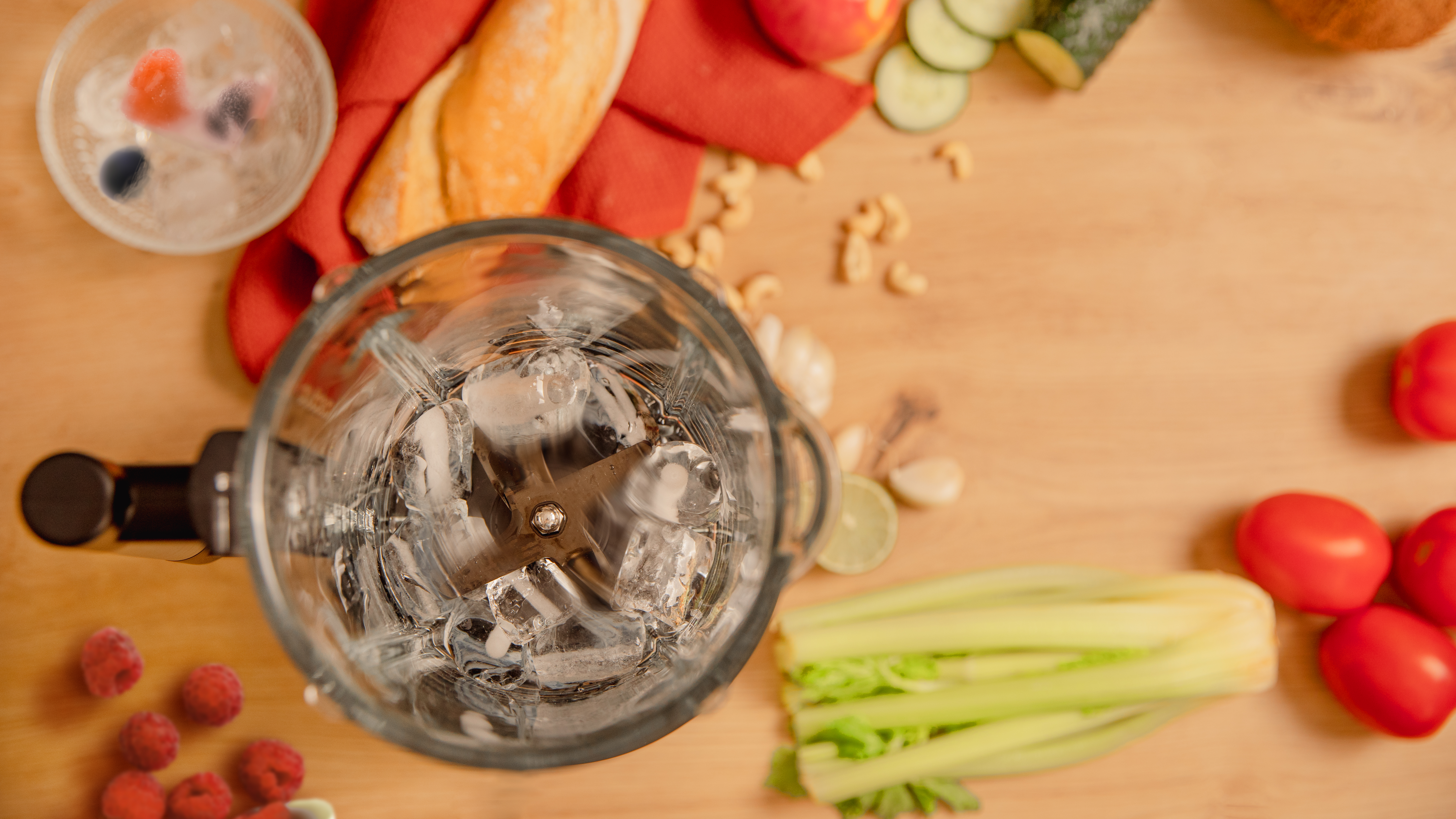 Licuadora con hielo e ingredientes sobre una mesa de madera.