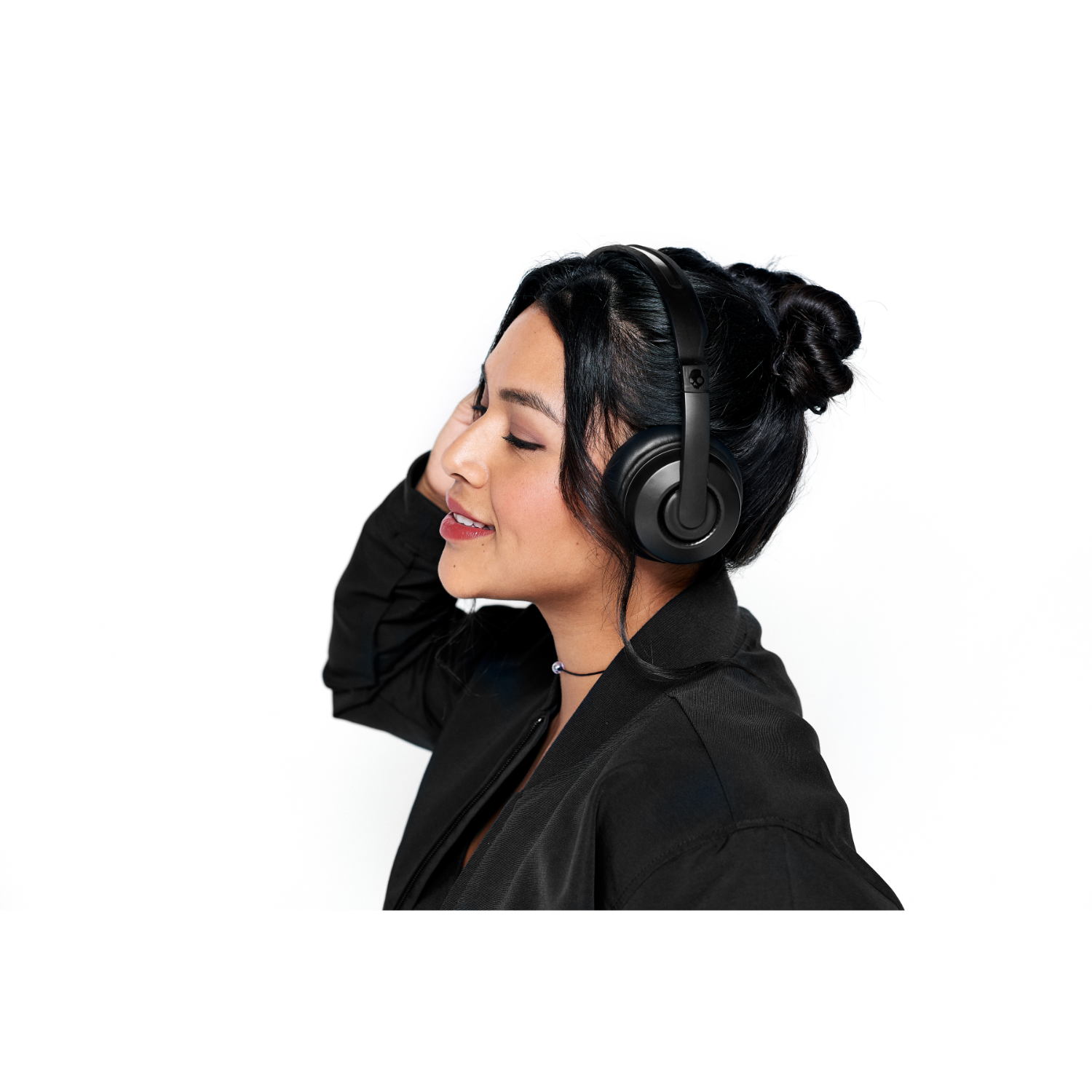 A woman with black hair wearing black headphones and a black jacket.