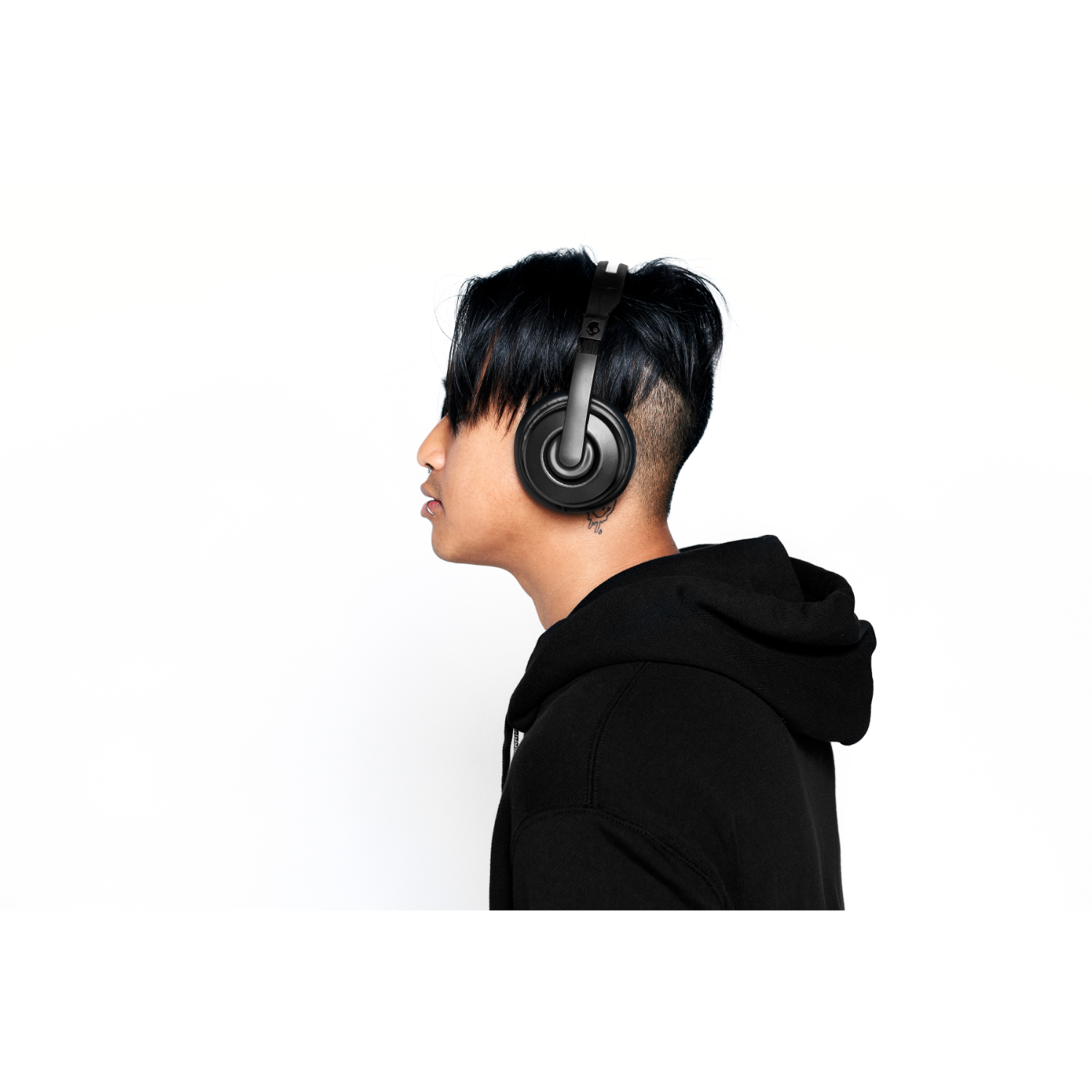 A person wearing black headphones and a black hoodie, white background.