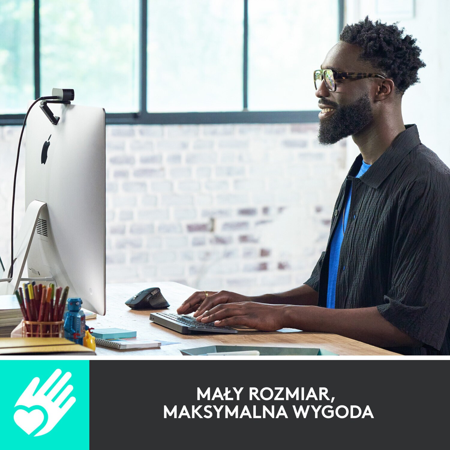 Mężczyzna używający klawiatury i myszy, z komputerem w tle.