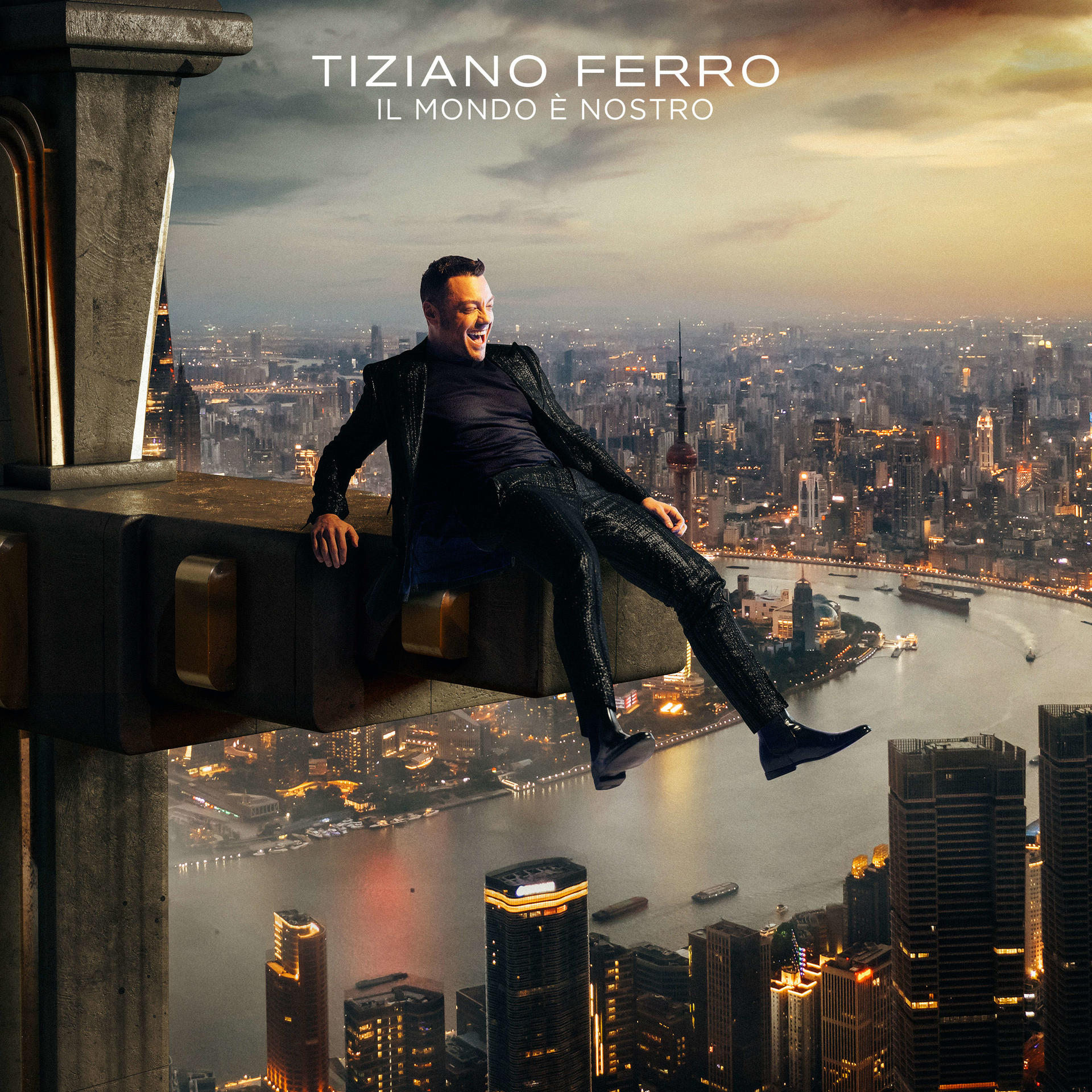 Mann sitzt auf einem Gebäude, Stadtlandschaft im Hintergrund. Albumcover mit Text: Tiziano Ferro.