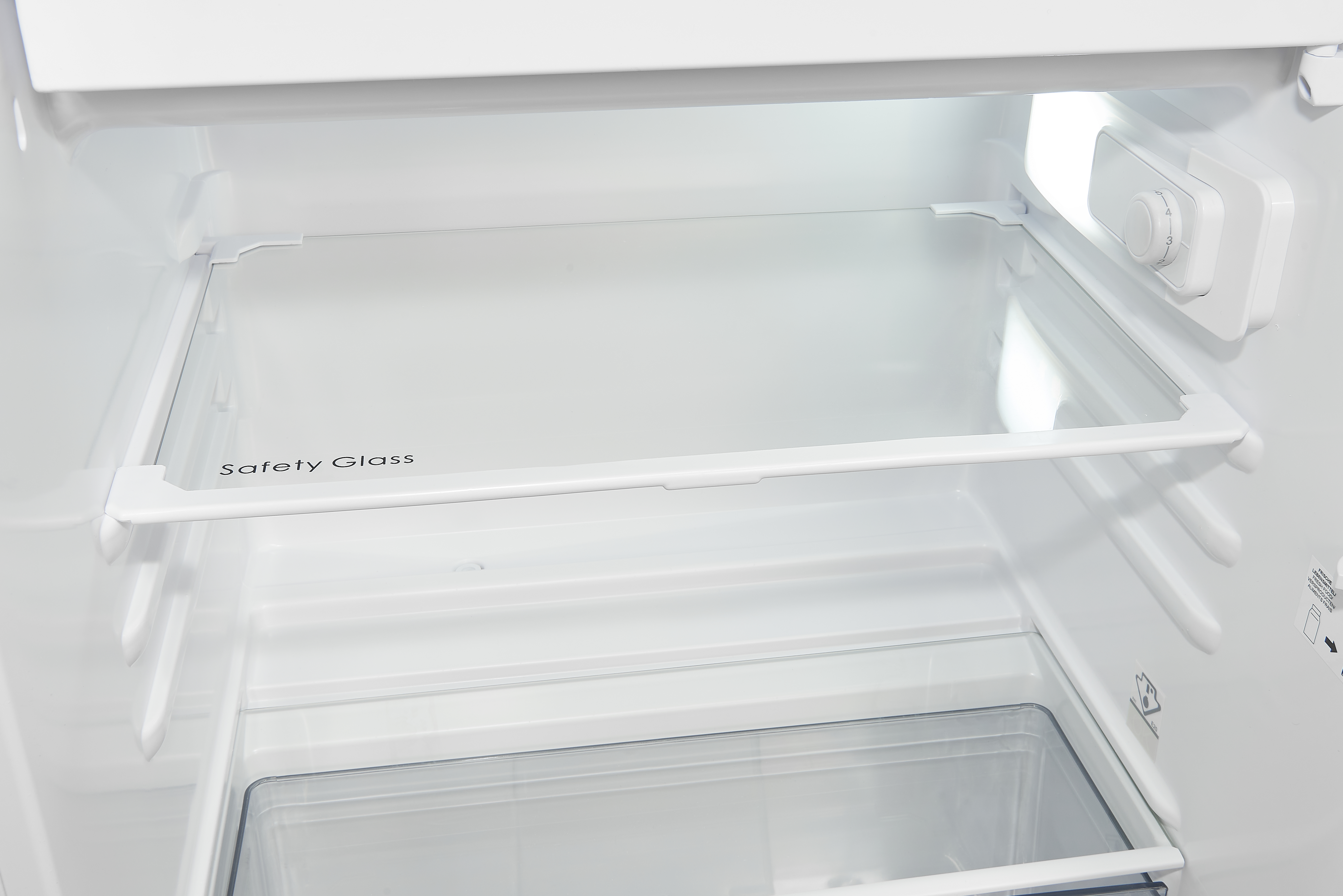 Inneres eines weißen Kühlschranks mit einem Glasregal mit der Aufschrift 'Safety Glass'.