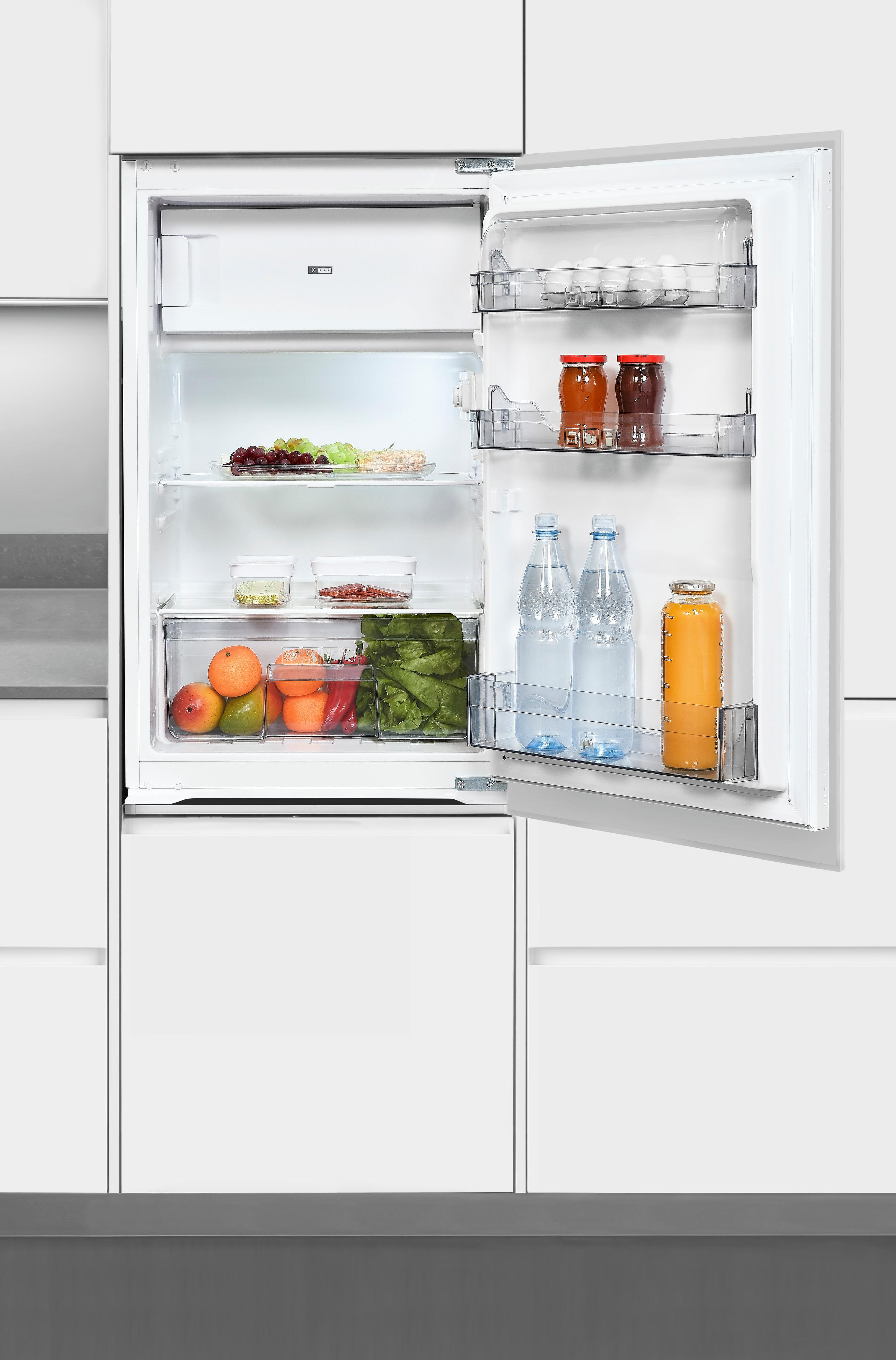 Geöffneter Kühlschrank mit Obst, Gemüse, Wasserflaschen und Gläsern.