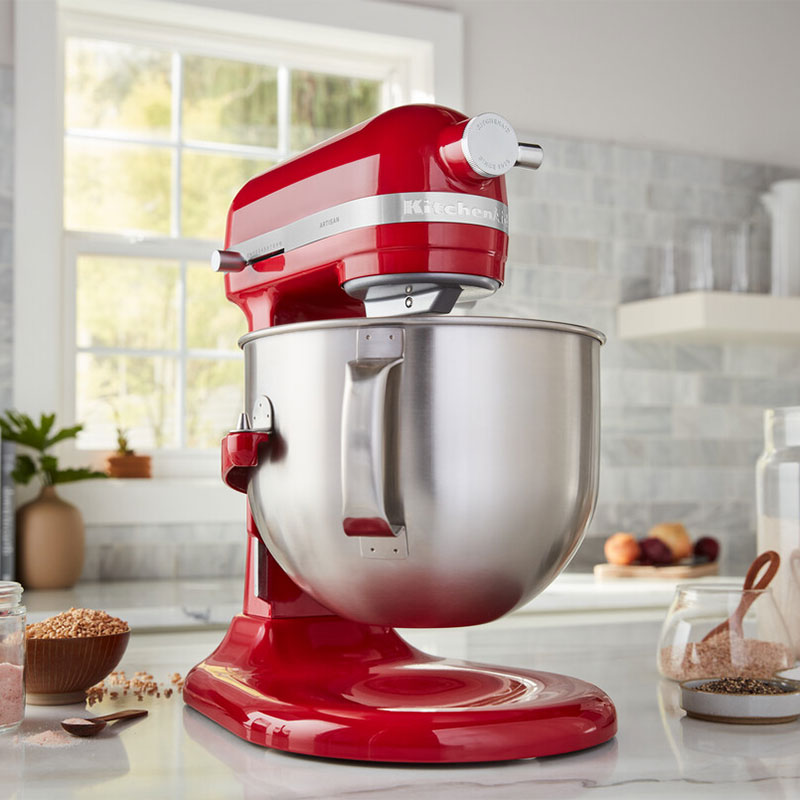 Egy piros KitchenAid állványos mixer rozsdamentes acél tálal, fehér pulton.