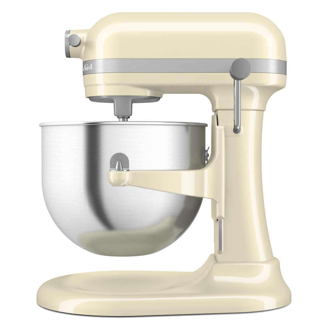 Krém színű KitchenAid robotgép. Ezüst tál és tartozékok. Fehér háttér.