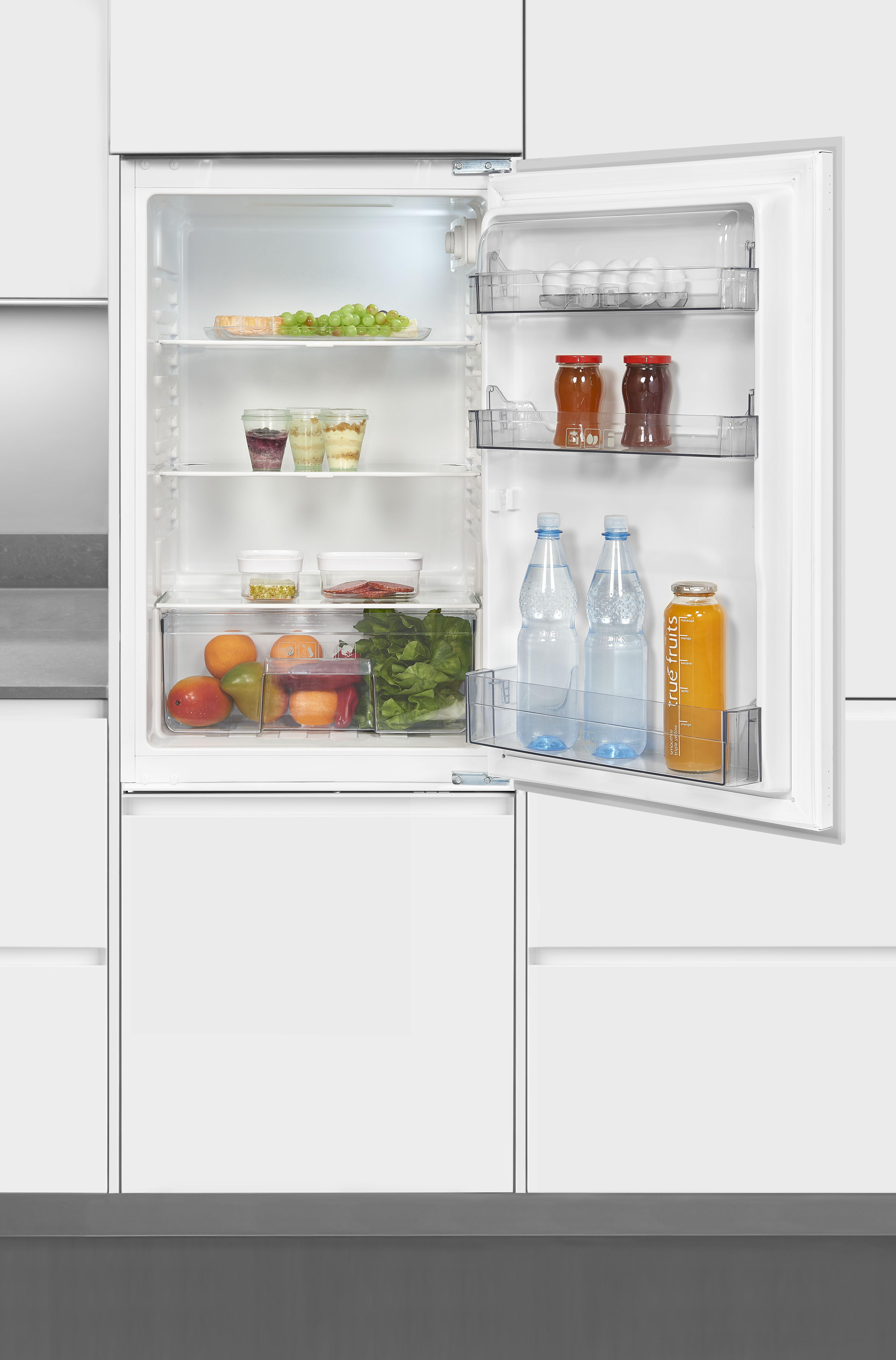 Kühlschrankinnenraum geöffnet. Enthält Lebensmittel: Obst, Gemüse, Getränke und Gläser. Weiße Türen und Regale.