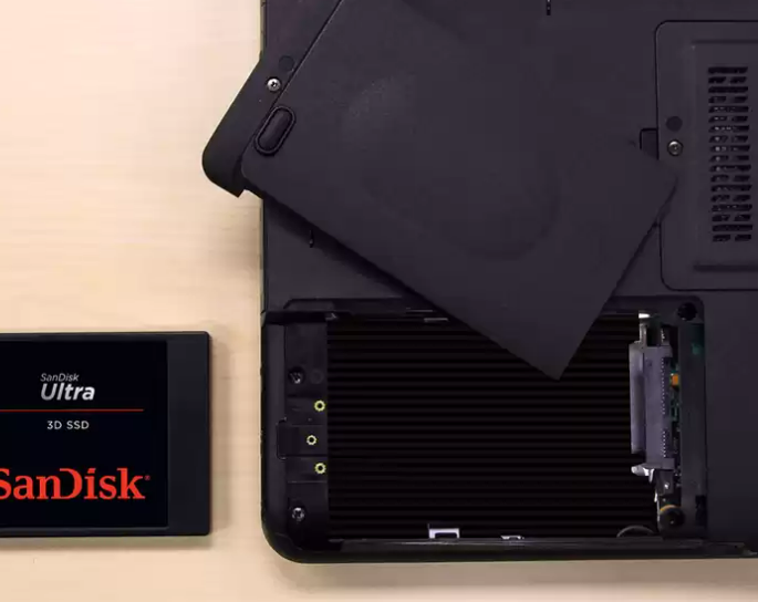 Laptop felemelt hátlappal, SanDisk SSD-t mutatva.