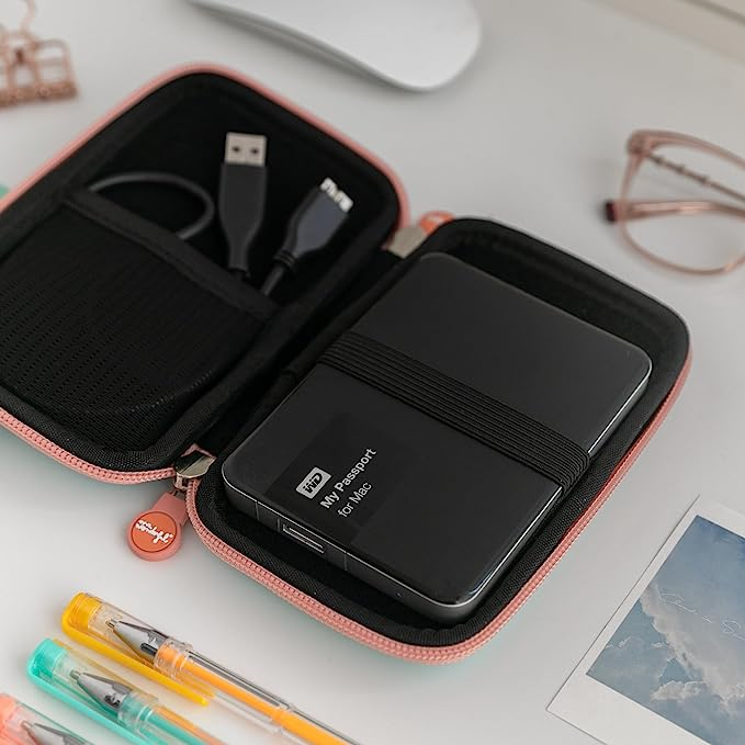 Estuche de disco duro abierto con disco duro negro y accesorios en un escritorio blanco.