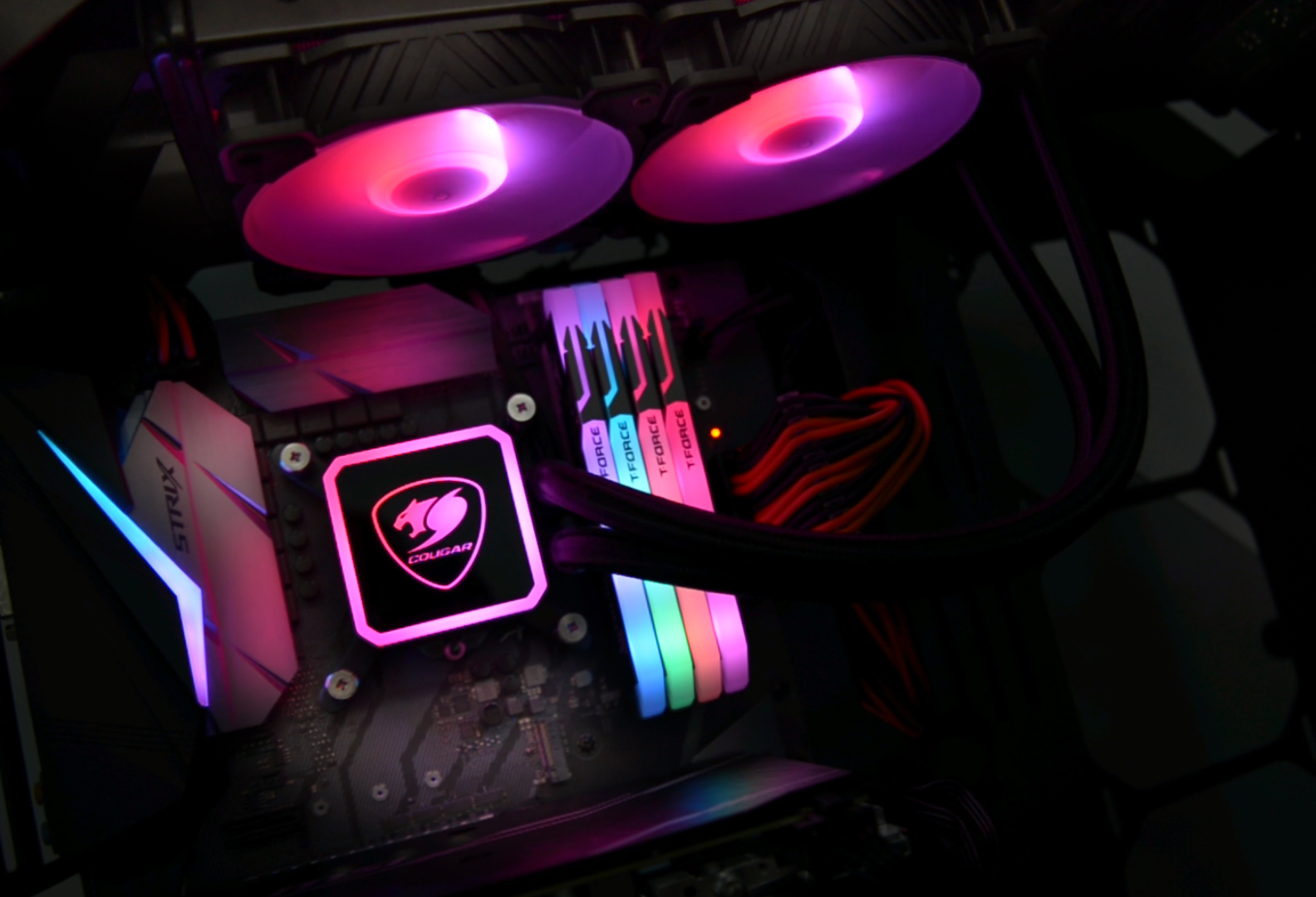 Egy kivilágított számítógép-beállítás, amely egy alaplapot, CPU-hűtőt és RAM-ot mutat, mindegyik színes fényekkel.