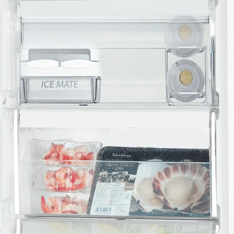 Wewnątrz lodówki. Widoczna kostkarka do lodu, krewetki i przegrzebki na półkach.