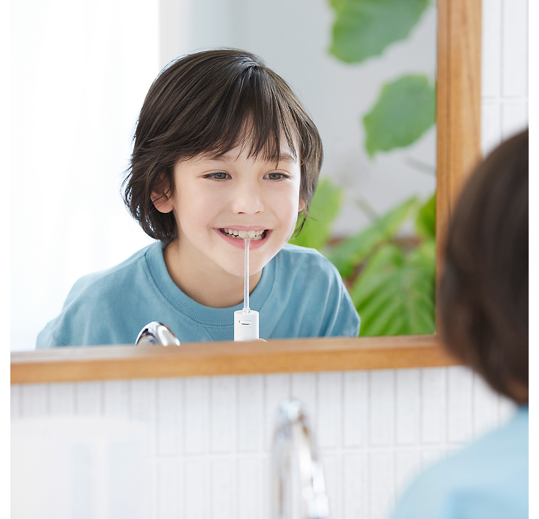 Un ragazzo si guarda allo specchio, usando un idropulsore.