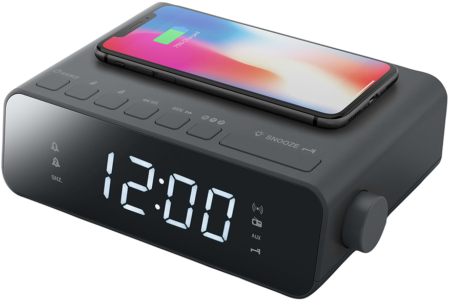 Egy szürke digitális ébresztőóra, tetején egy telefonnal. Az óra 12:00-t mutat, és gombokkal rendelkezik.