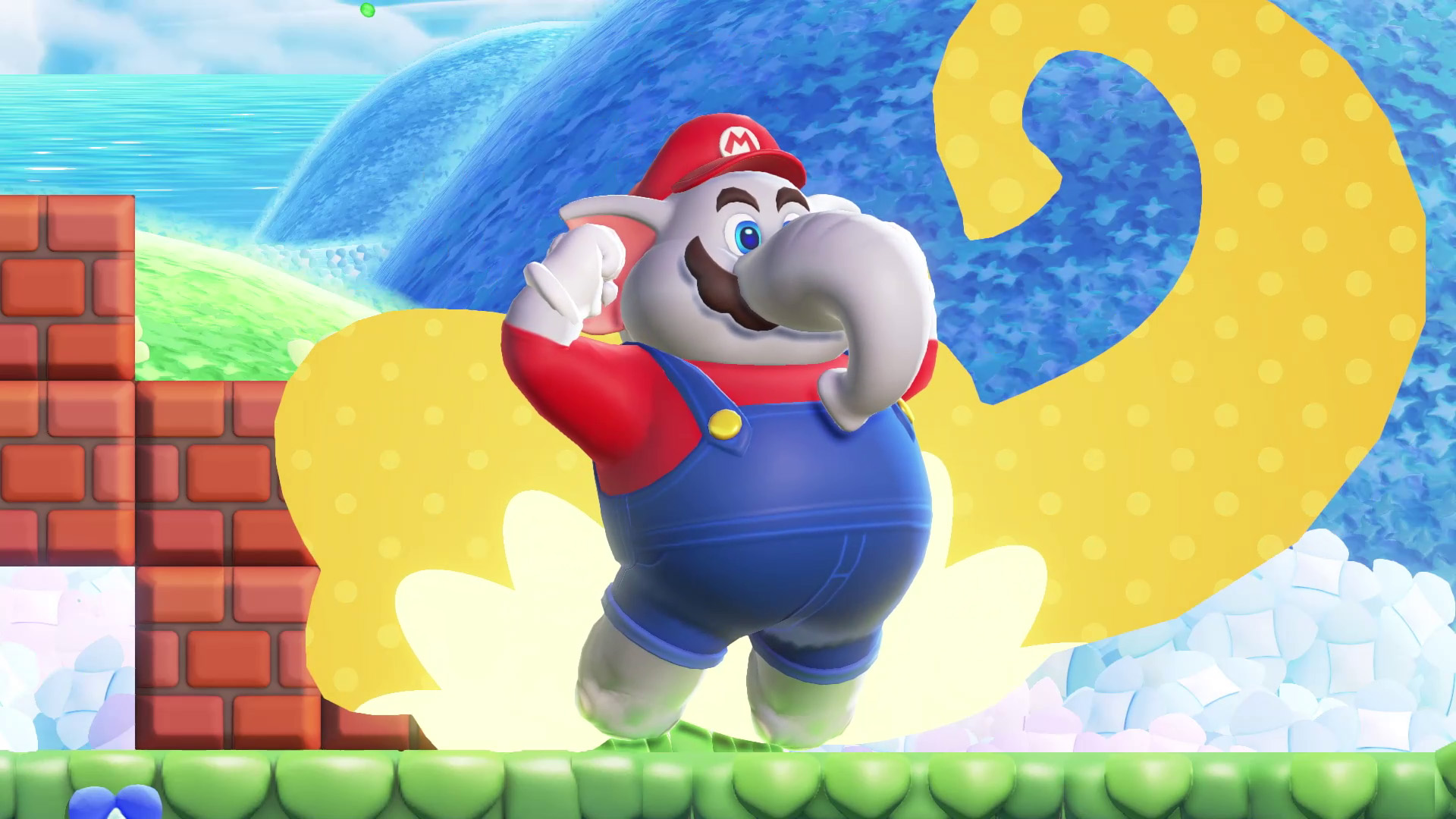 Mario als Elefant springt, mit gelbem Splash dahinter, auf buntem Hintergrund.