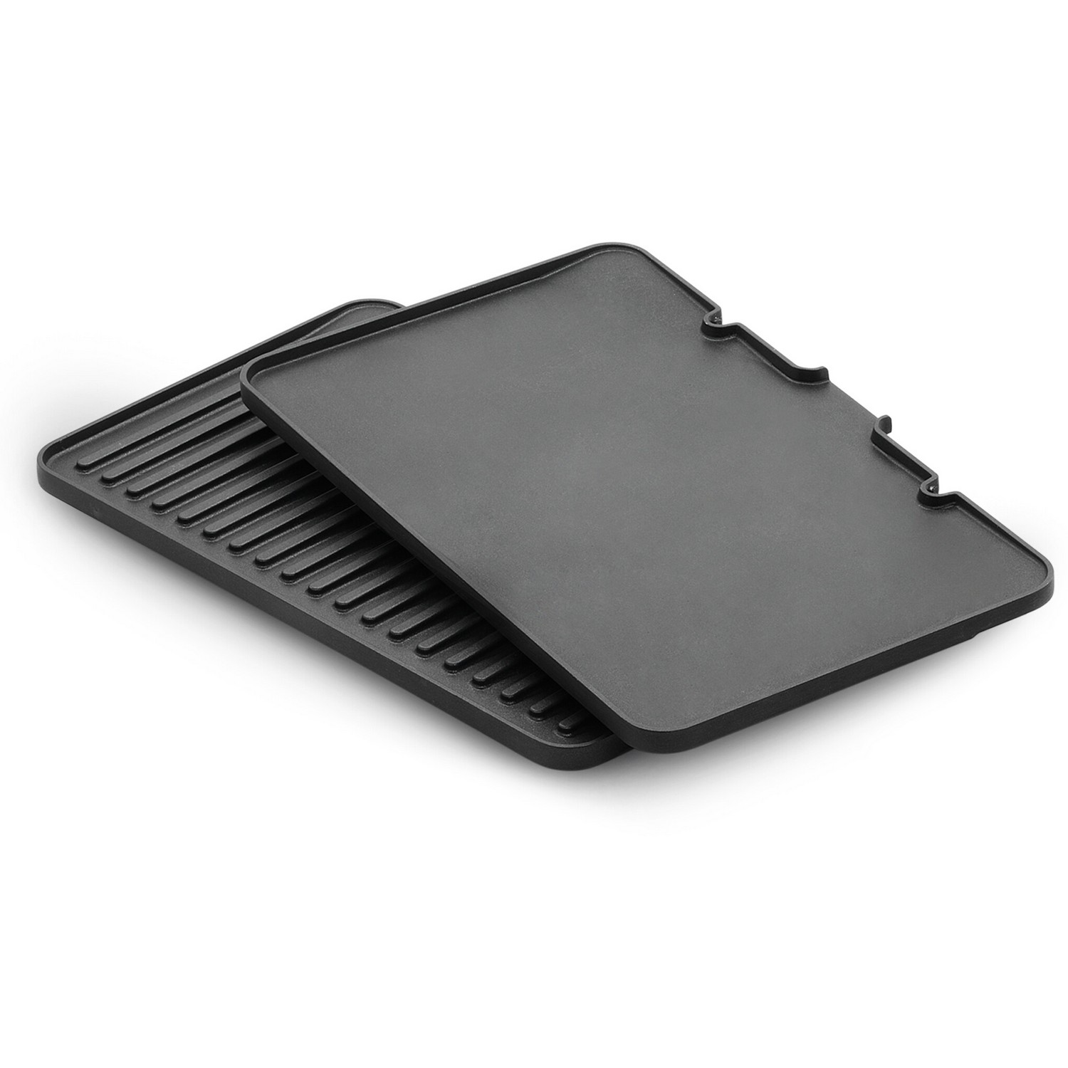 Twee zwarte grillplaten. Eén heeft grilllijnen, de andere is plat. Witte achtergrond.