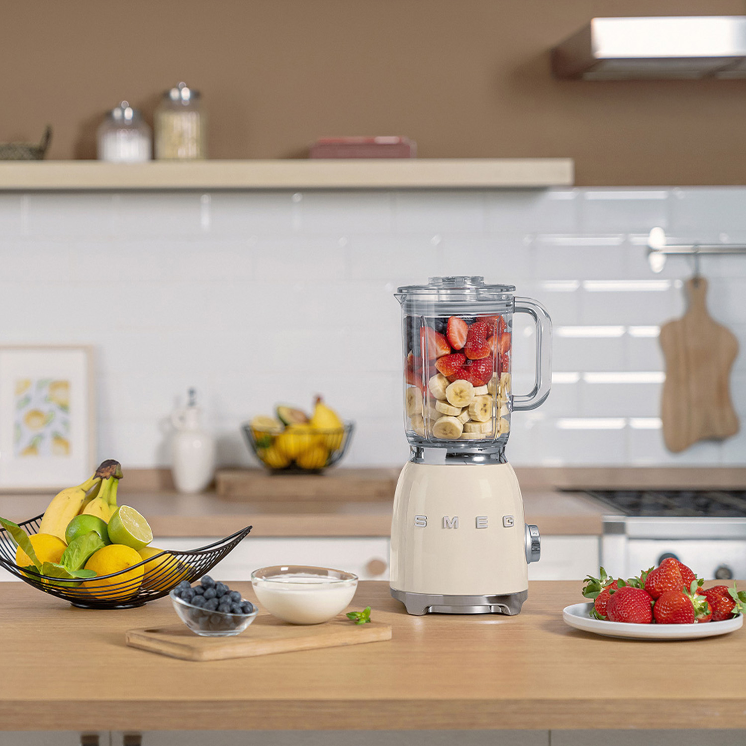 Frullatore con frutta, banane, fragole, su un piano di legno.