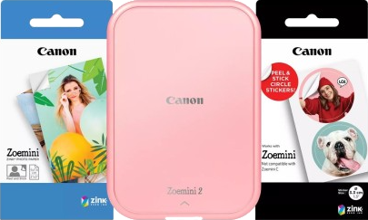 Une imprimante rose Canon Zoemini 2 avec du papier photo et des paquets d'autocollants.