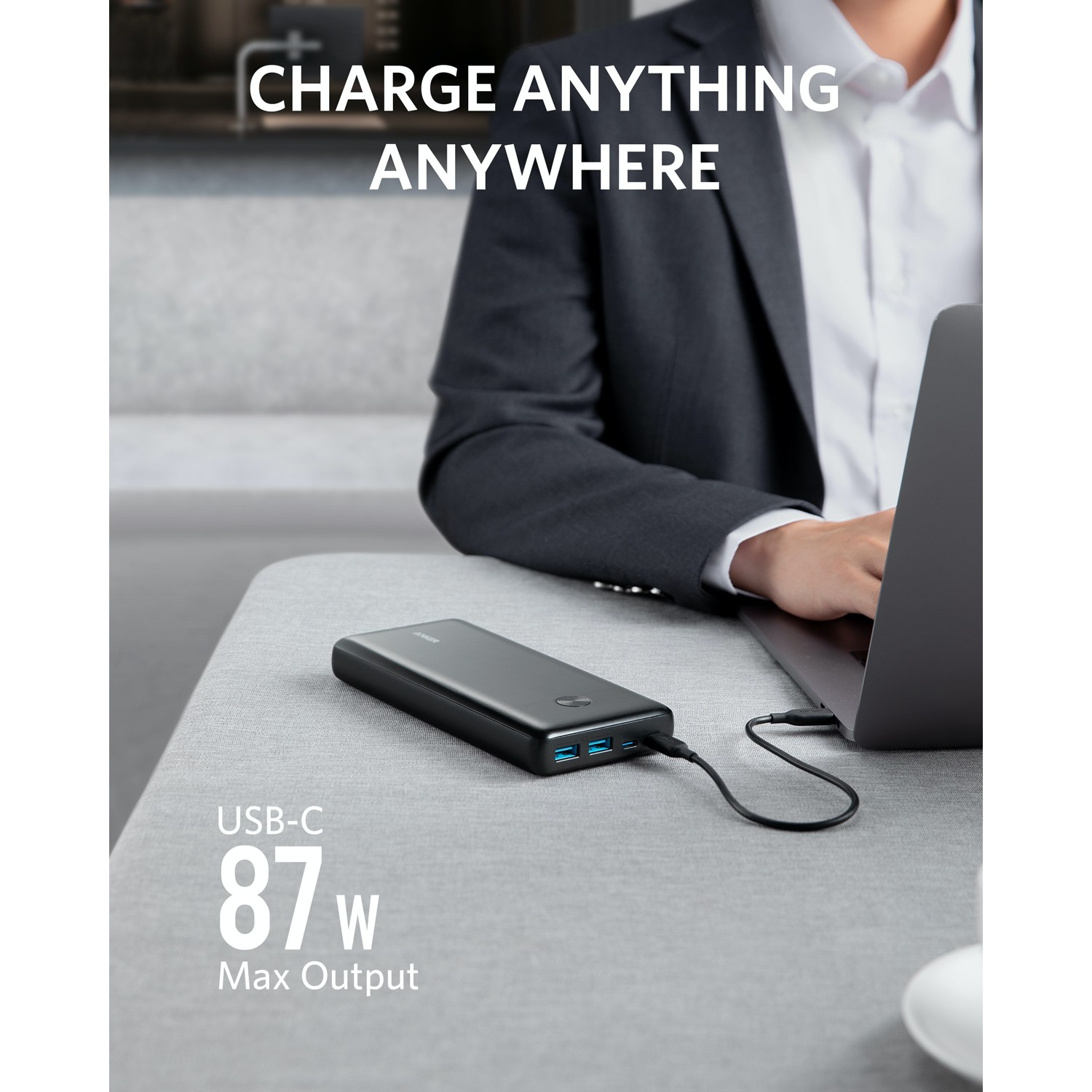 A person charging a laptop with a black power bank. The text says 'Charge Anything Anywhere'.