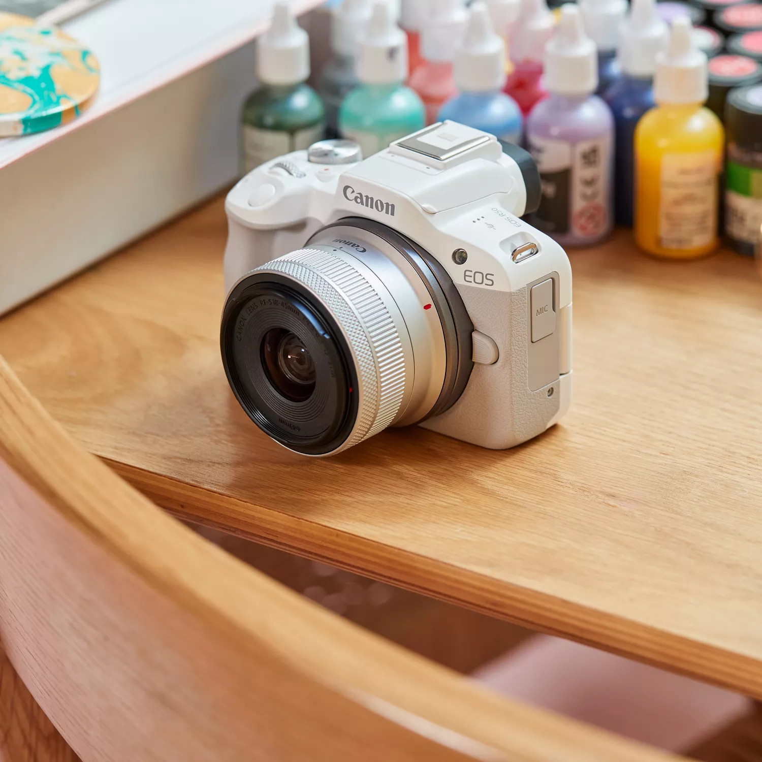 White Canon EOS camera on a wooden surface.