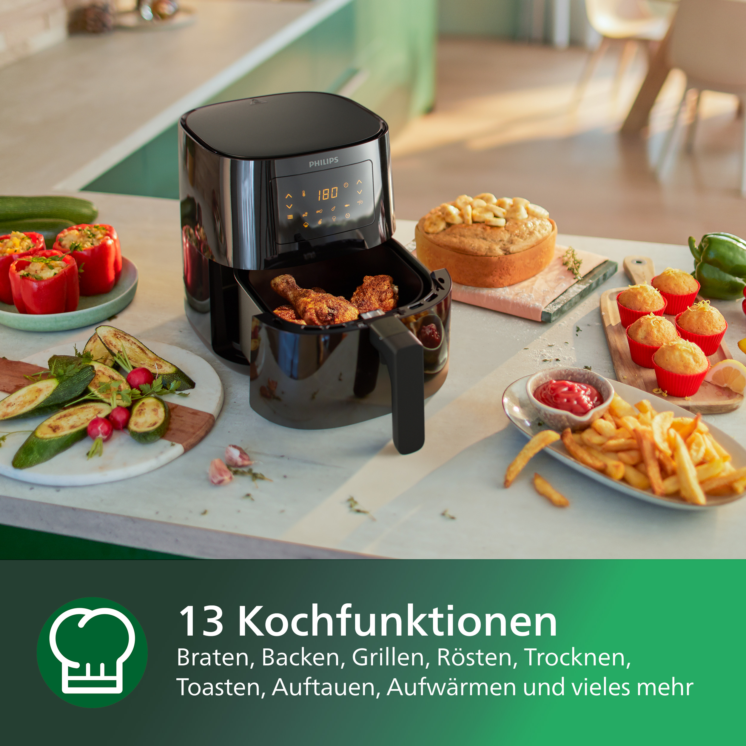 Eine Heißluftfritteuse mit Essen und verschiedene Gerichte auf einem Tisch. Enthält Pommes, Muffins und Paprika.