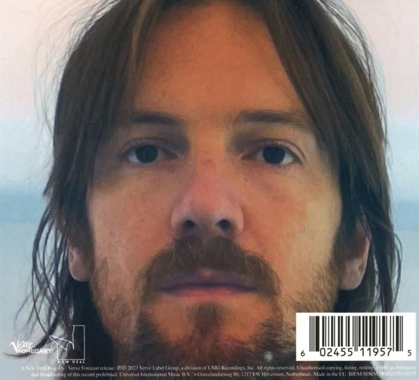 Nahaufnahme eines Mannes mit braunen Haaren und Bart, mit verschwommenem Hintergrund.