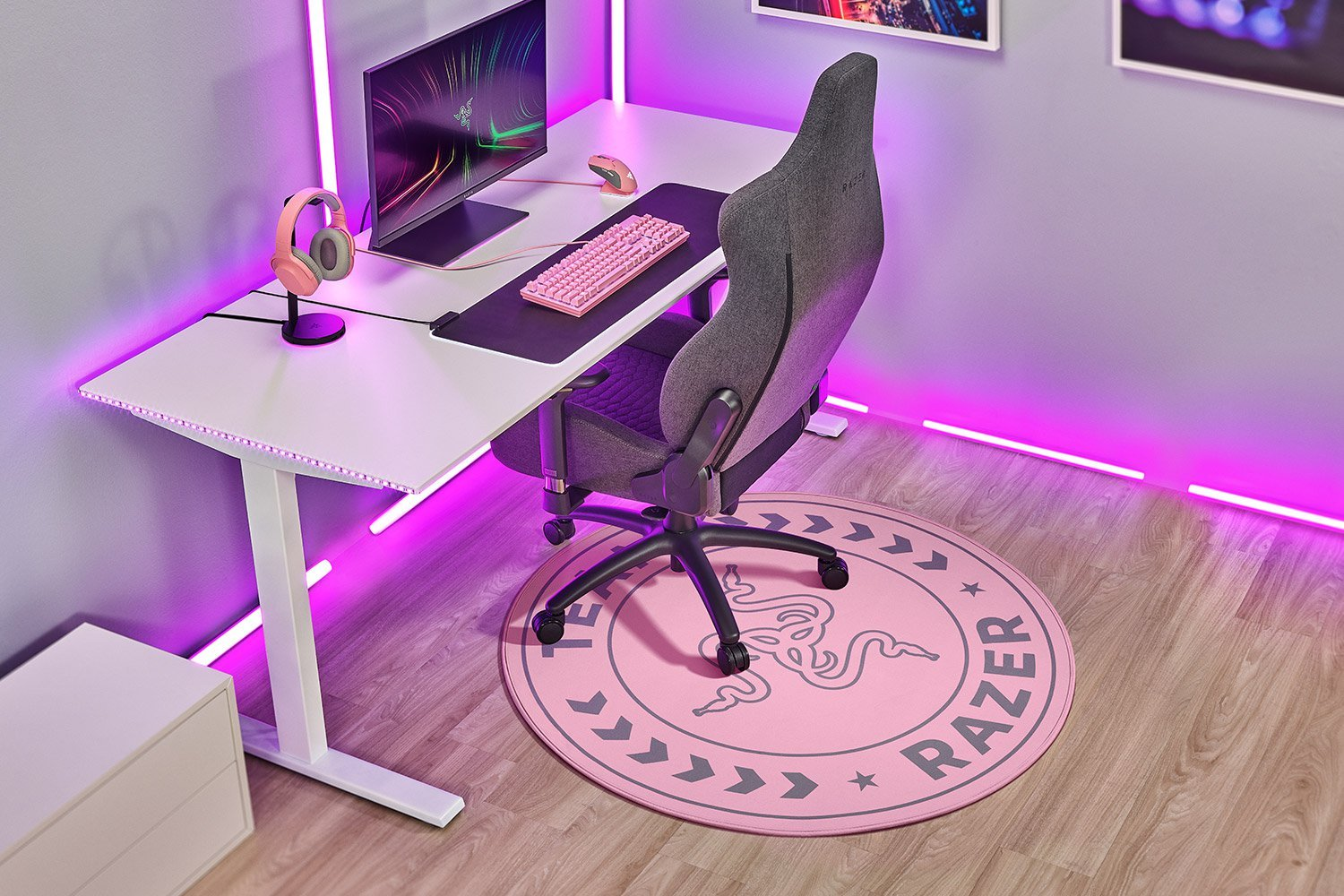 Gaming-Setup mit weißem Schreibtisch, pinkfarbener Tastatur, Headset und pinkfarbenem Razer-Mauspad. Pinkfarbene Neonlichter.