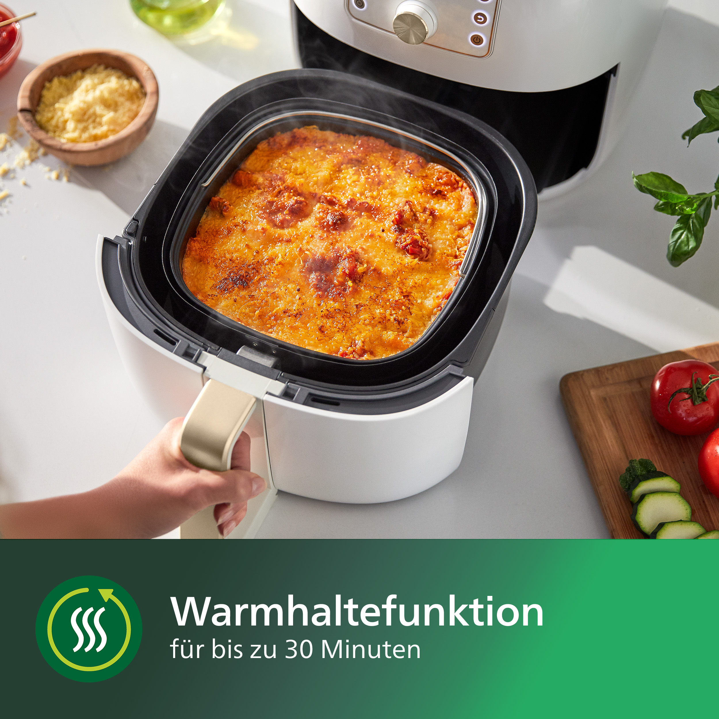 Fritteuse mit quadratischem Gericht und Hand am Griff.