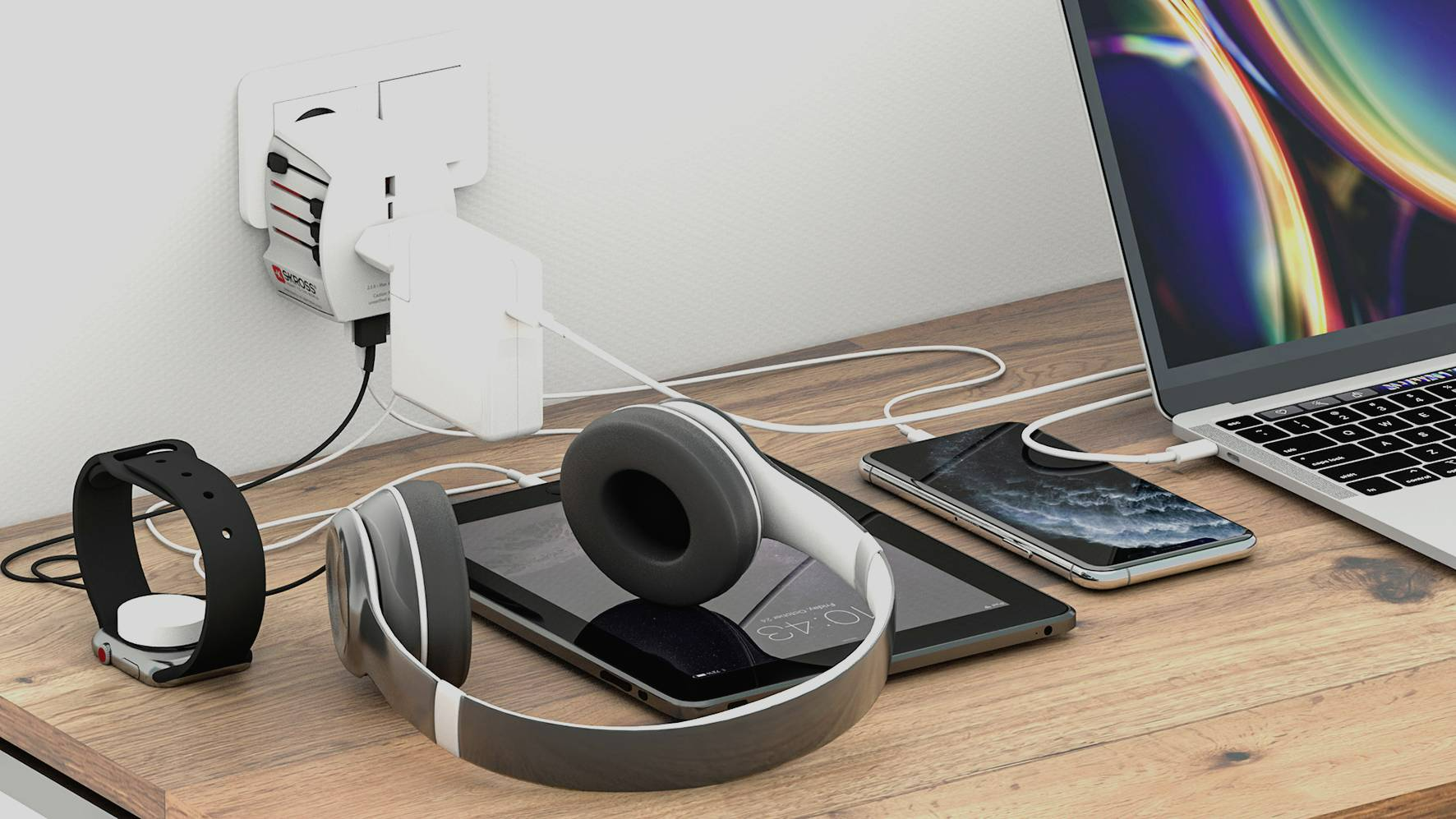 Eszközök töltése fa asztalon: laptop, telefon, tablet, fejhallgató, óra, adapter.