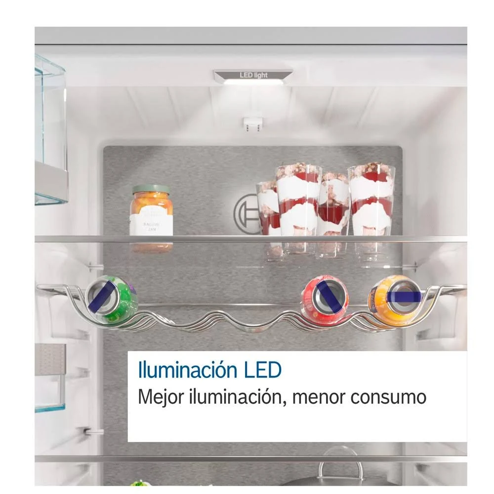 Interior de refrigerador con estantes. Frascos de comida, latas y postres son visibles en el refrigerador.