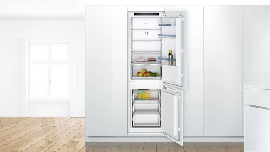Un refrigerador blanco con la puerta abierta, revelando estantes, cajones y alimentos en el interior.