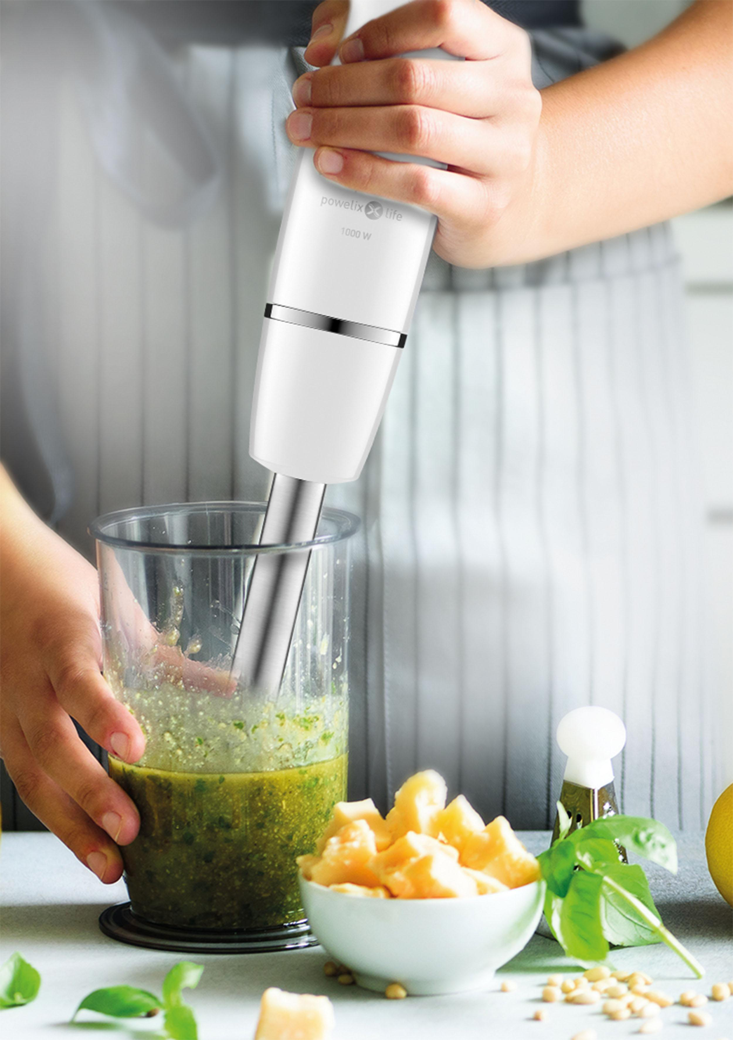 Eine Person benutzt einen weißen Stabmixer und vermischt Zutaten in einem Glas.