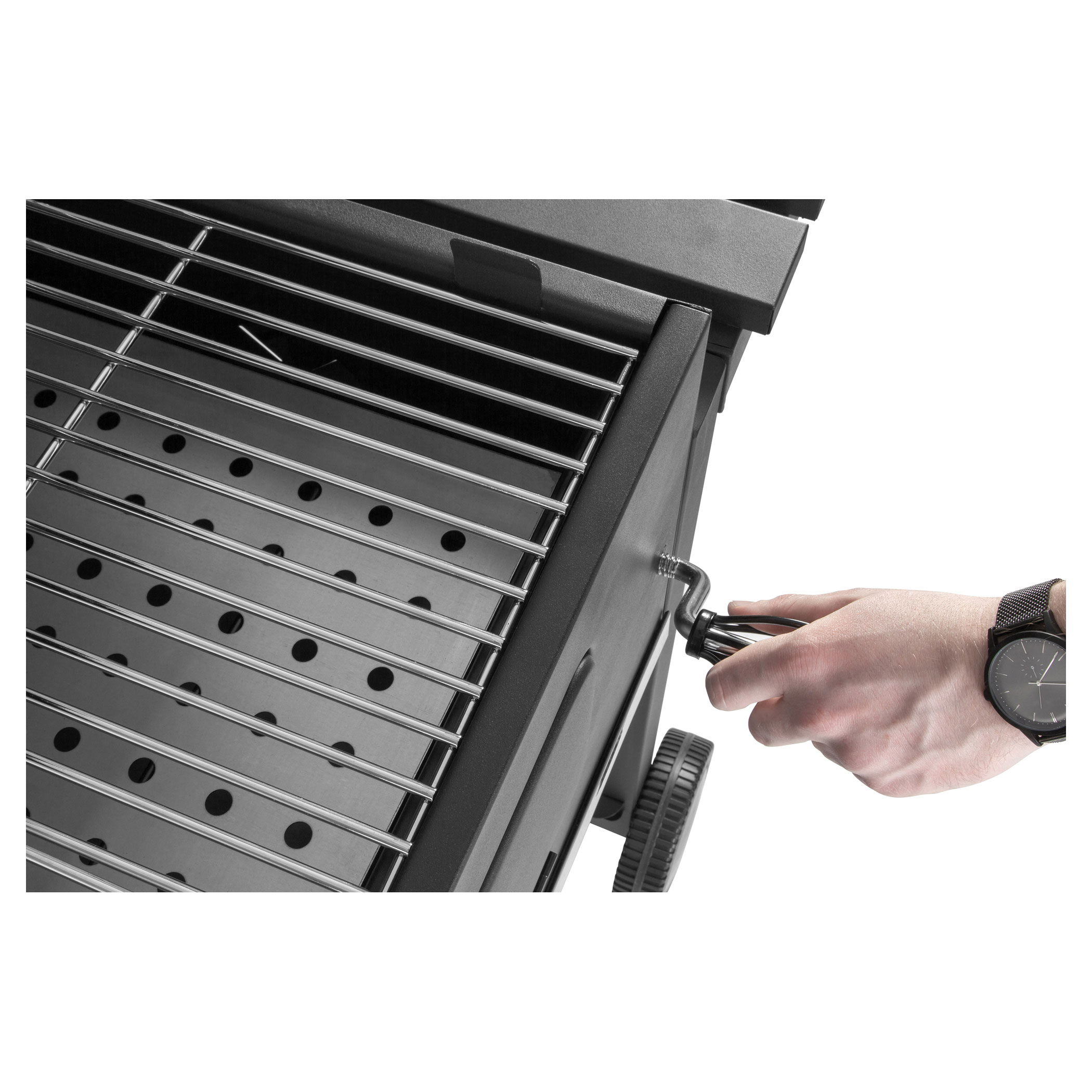 Egy személy keze egy fekete barbecue grill fogantyúját forgatja. Egy óra látható.