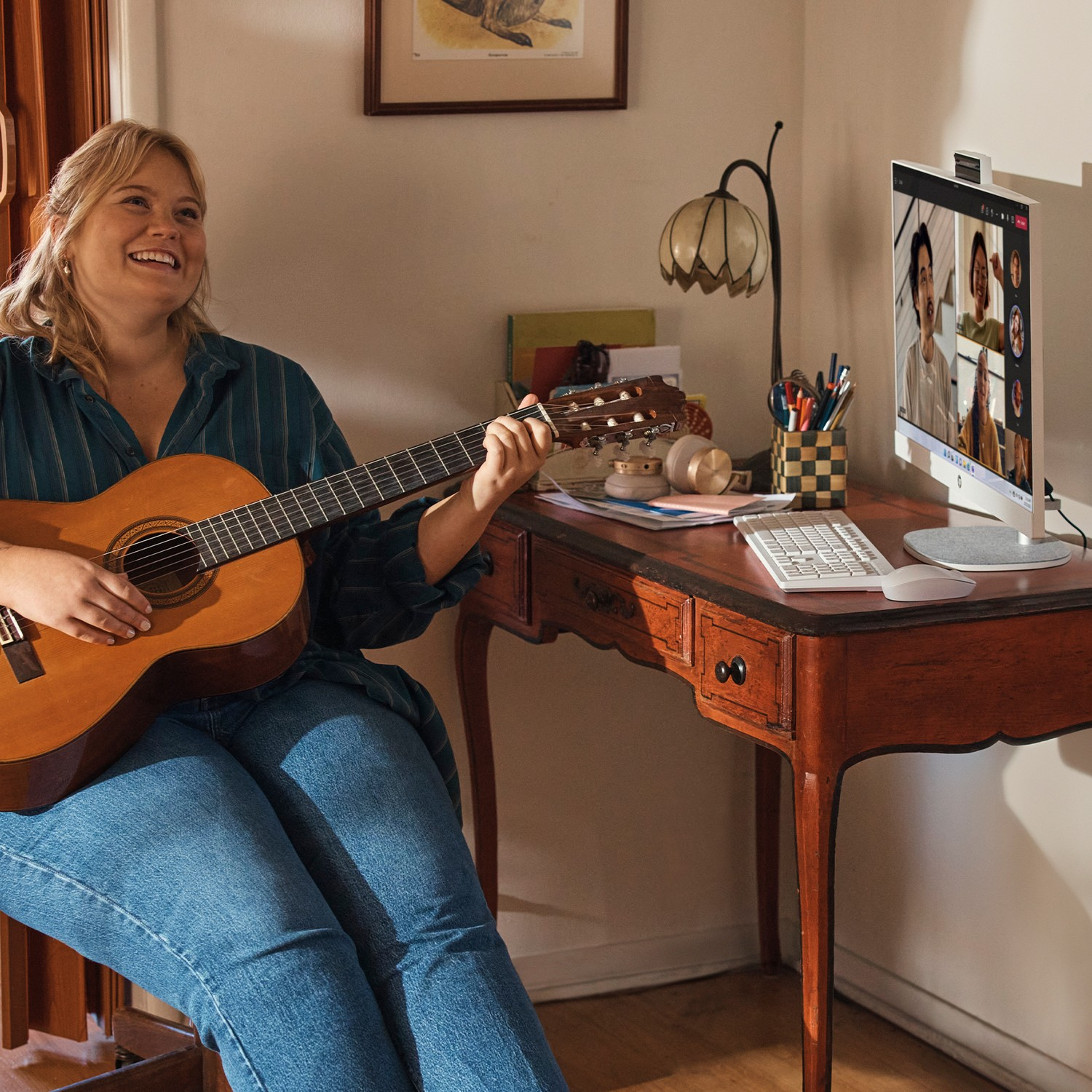 Woman playing guitar, video call on a monitor.