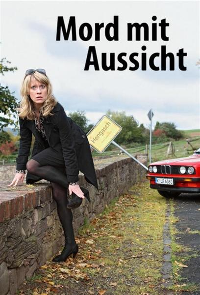 Eine Frau in einem schwarzen Kleid posiert neben einem roten Auto und einem Schild mit der Aufschrift 'Hengasch'. Ein bewölkter Himmel ist im Hintergrund.