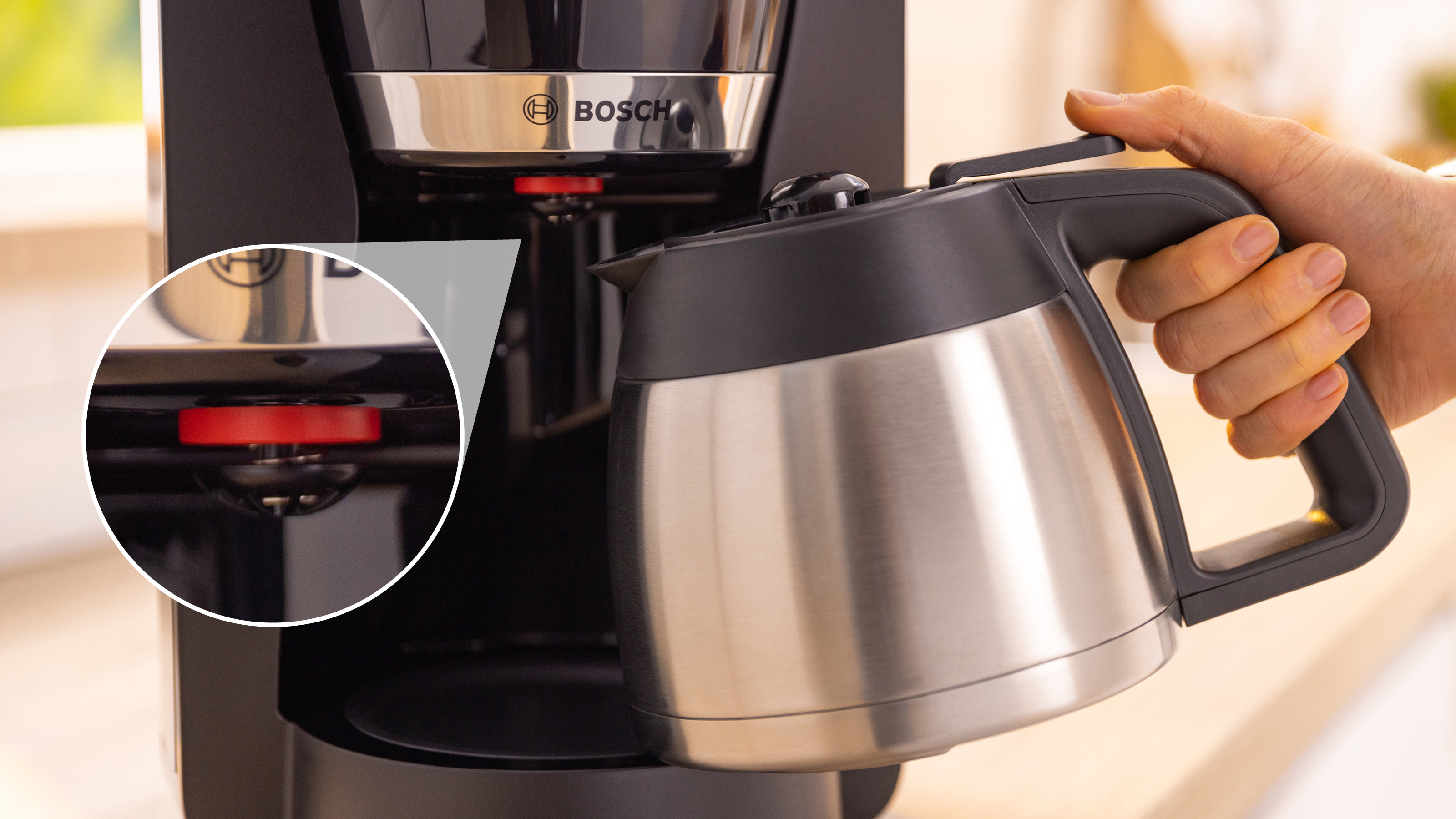 Eine Person gießt Kaffee aus einer Edelstahlkaraffe in eine Kaffeemaschine.