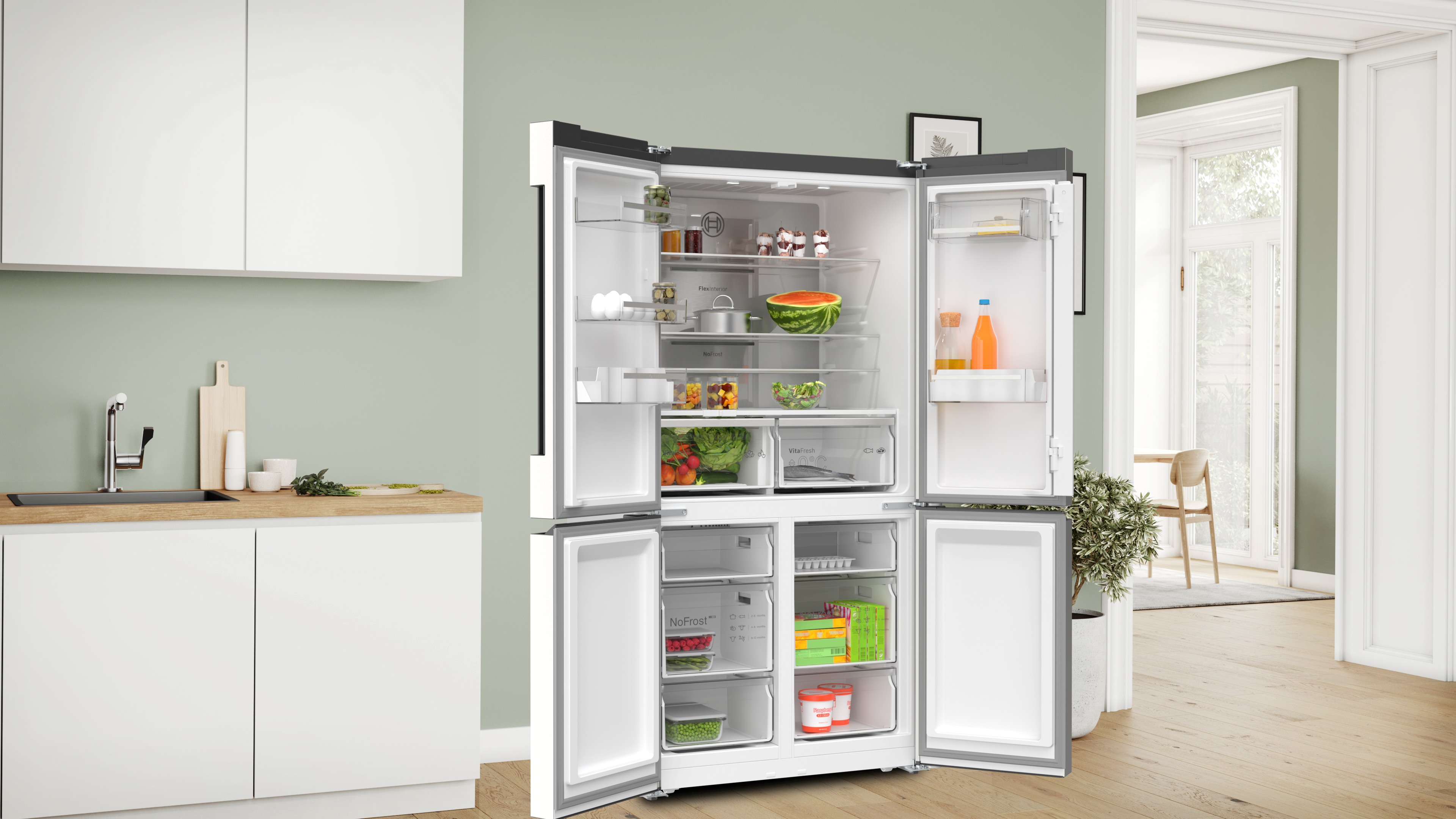 Ein Kühlschrank mit offenen Türen. Im Inneren befinden sich Regale mit Lebensmitteln. Die Küche ist weiß und grün.